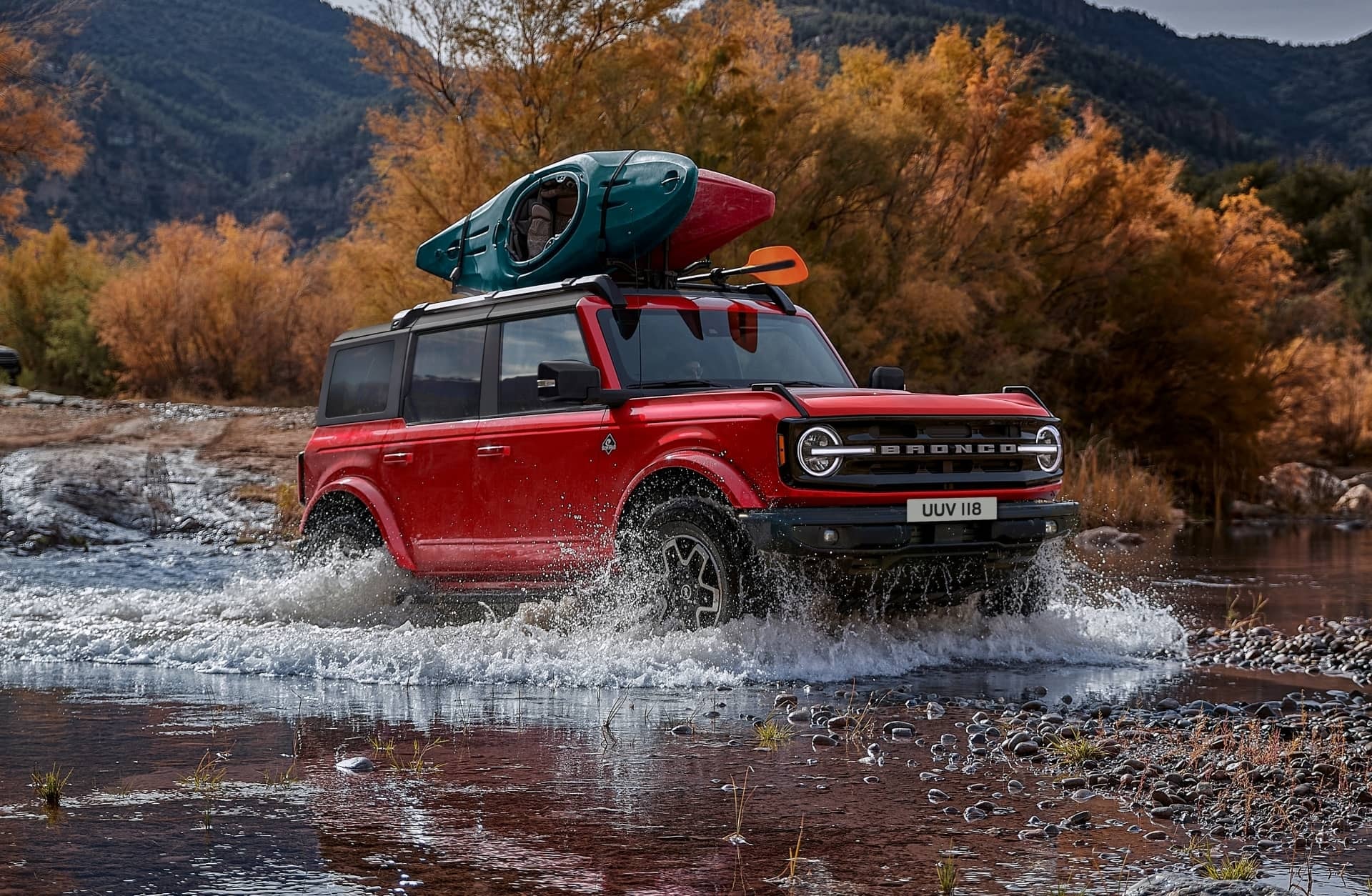 Ford Bronco cruzando un río con equipamiento de kayak, destacando su versatilidad.