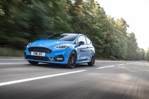 Ford Fiesta en movimiento, vista delantera y lateral, color azul. Ford Fiesta en movimiento, vista delantera y lateral, color azul.
