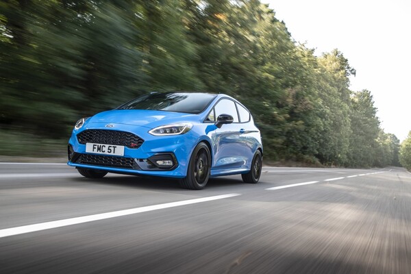 Ford Fiesta en movimiento, vista delantera y lateral, color azul.