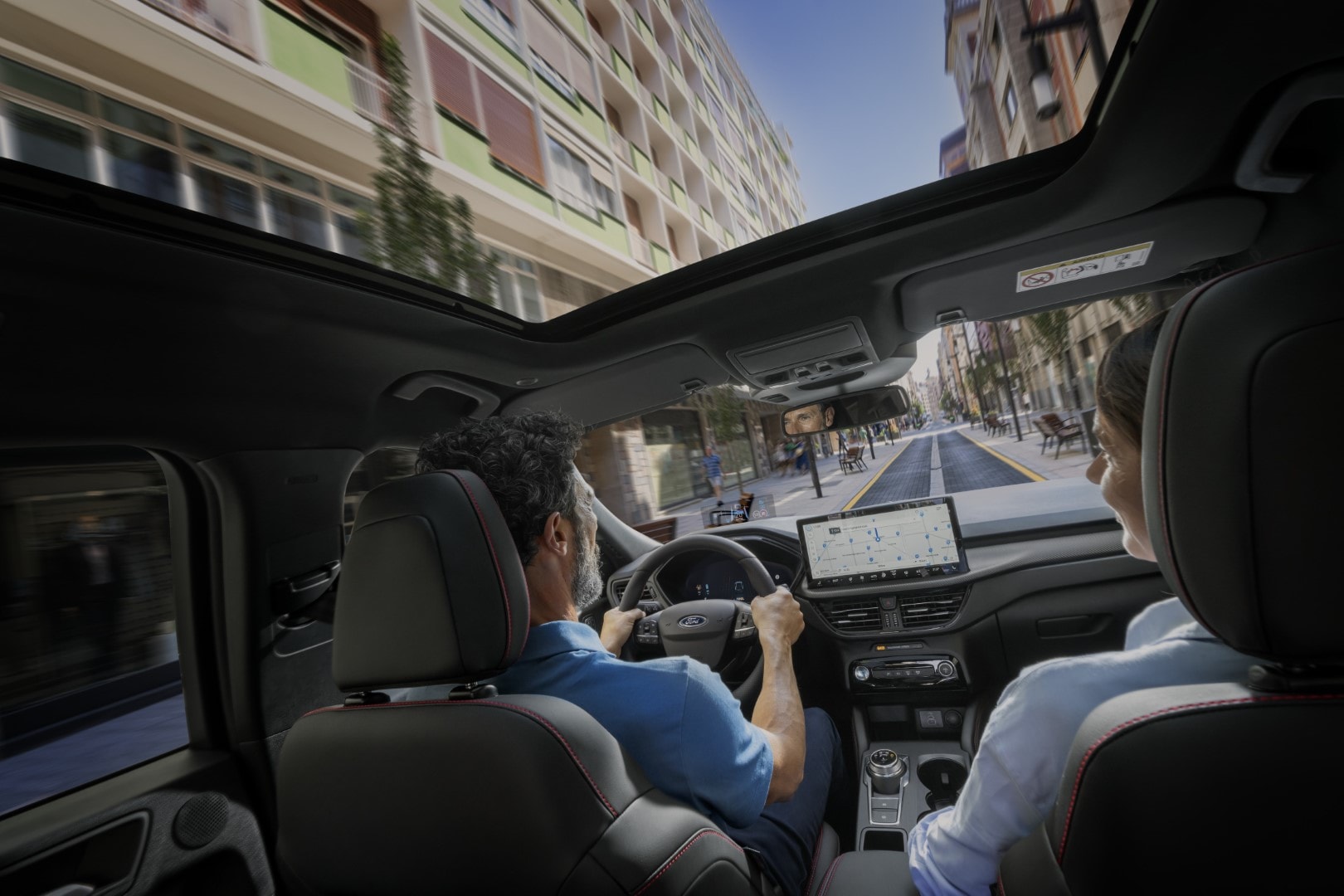 Vista interior del techo solar del Ford Kuga con pasajeros disfrutando del viaje.