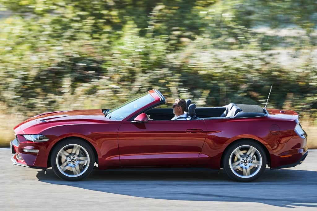 Mustang Cabrio en movimiento mostrando su perfil dinámico.