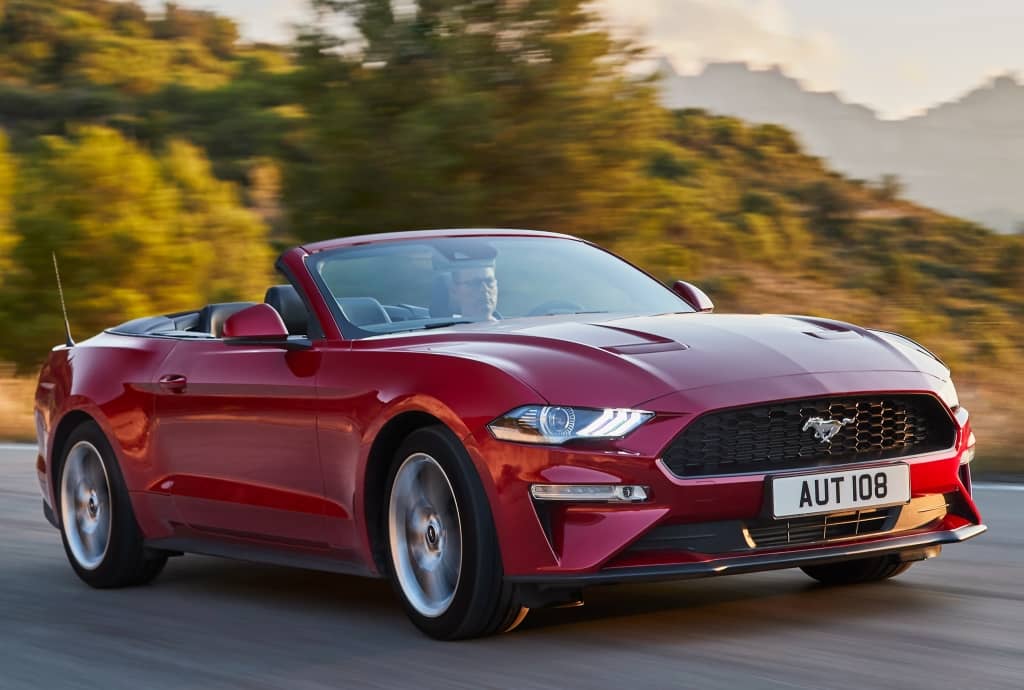 Imagen dinámica del Mustang Cabrio conduciendo, resaltando su deportividad.