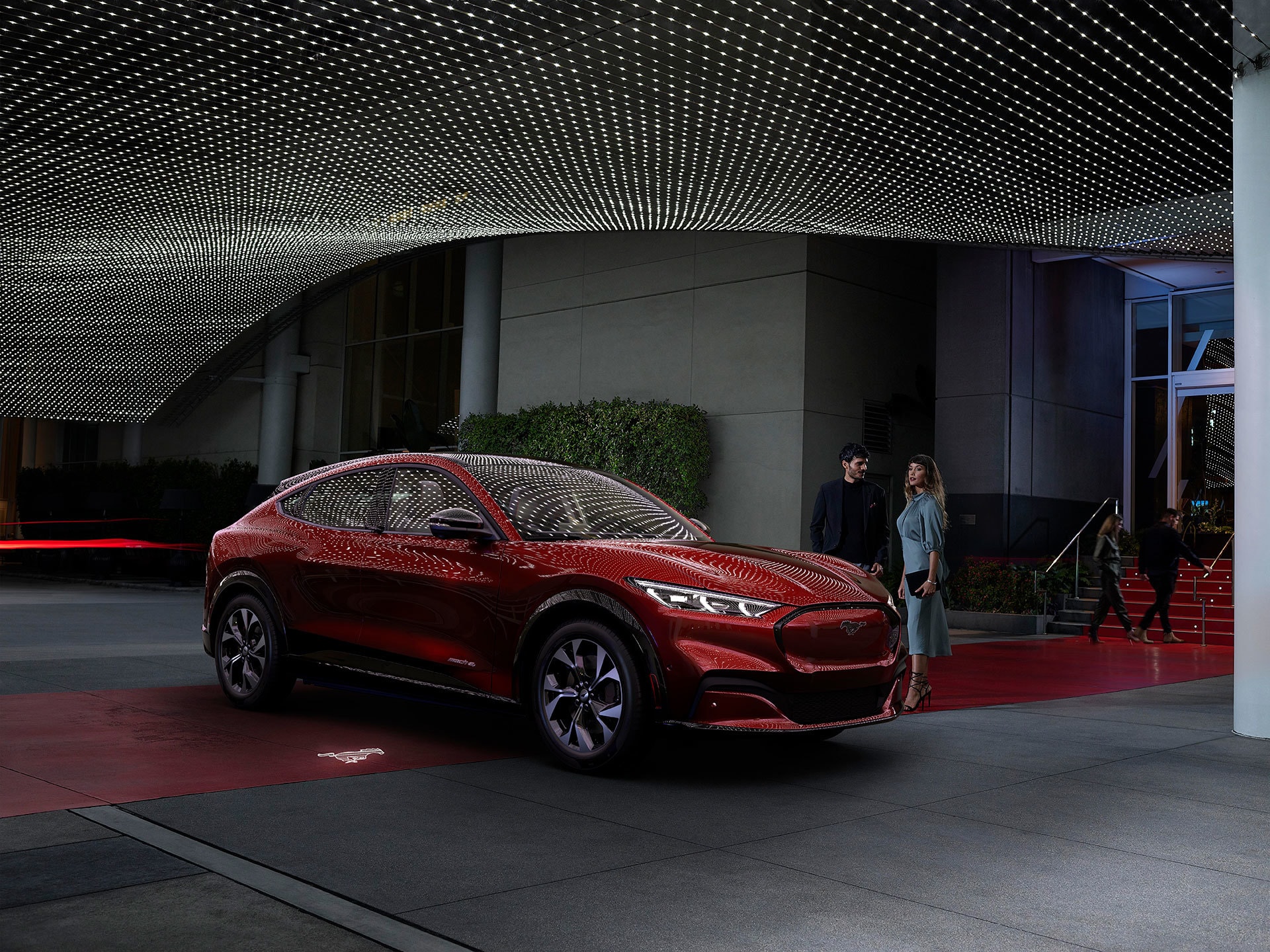 Vista lateral del Mustang Mach-E estacionado frente a un hotel.