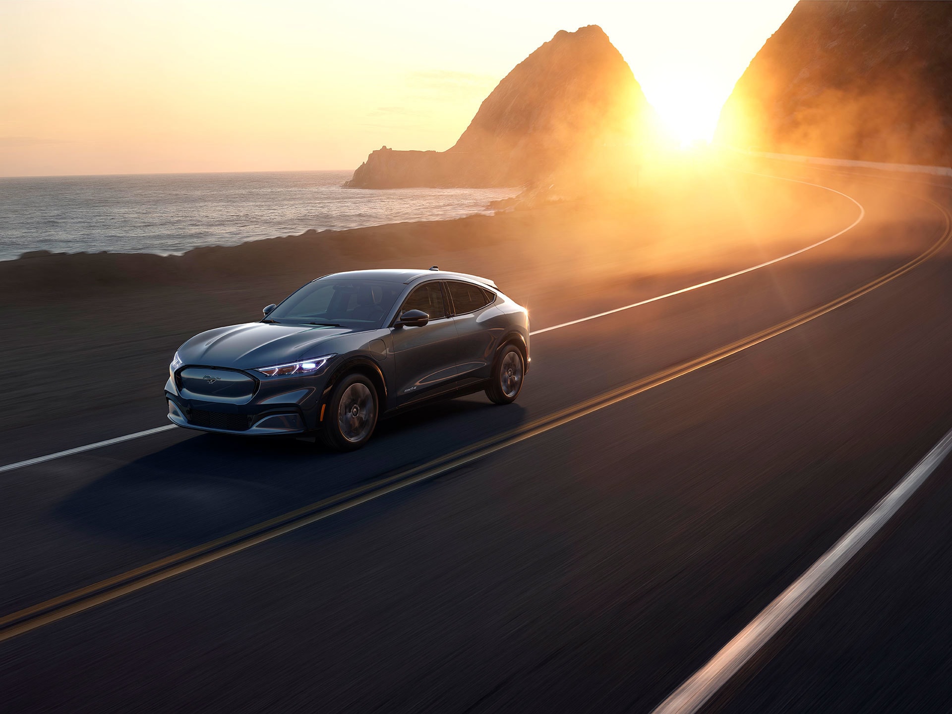 Imagen del Mach-E desde una perspectiva trasera lateral en carretera.