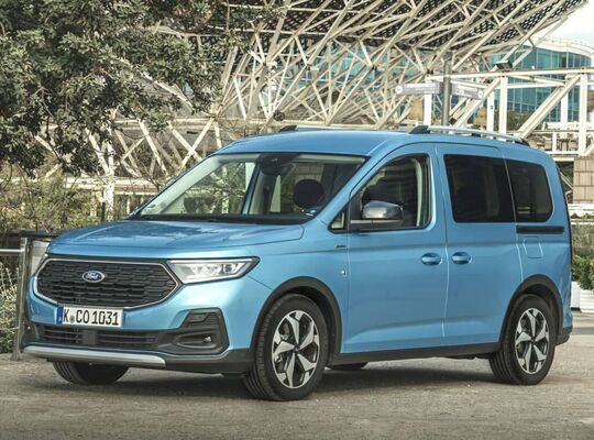 Ford Tourneo Connect azul lateral estacionado frente a estructura moderna Ford Tourneo Connect azul lateral estacionado frente a estructura moderna