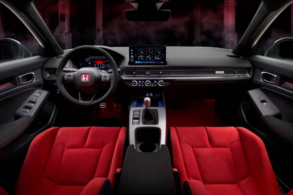 Cockpit racing, asientos deportivos tonalidad roja marcada y acabados premium.