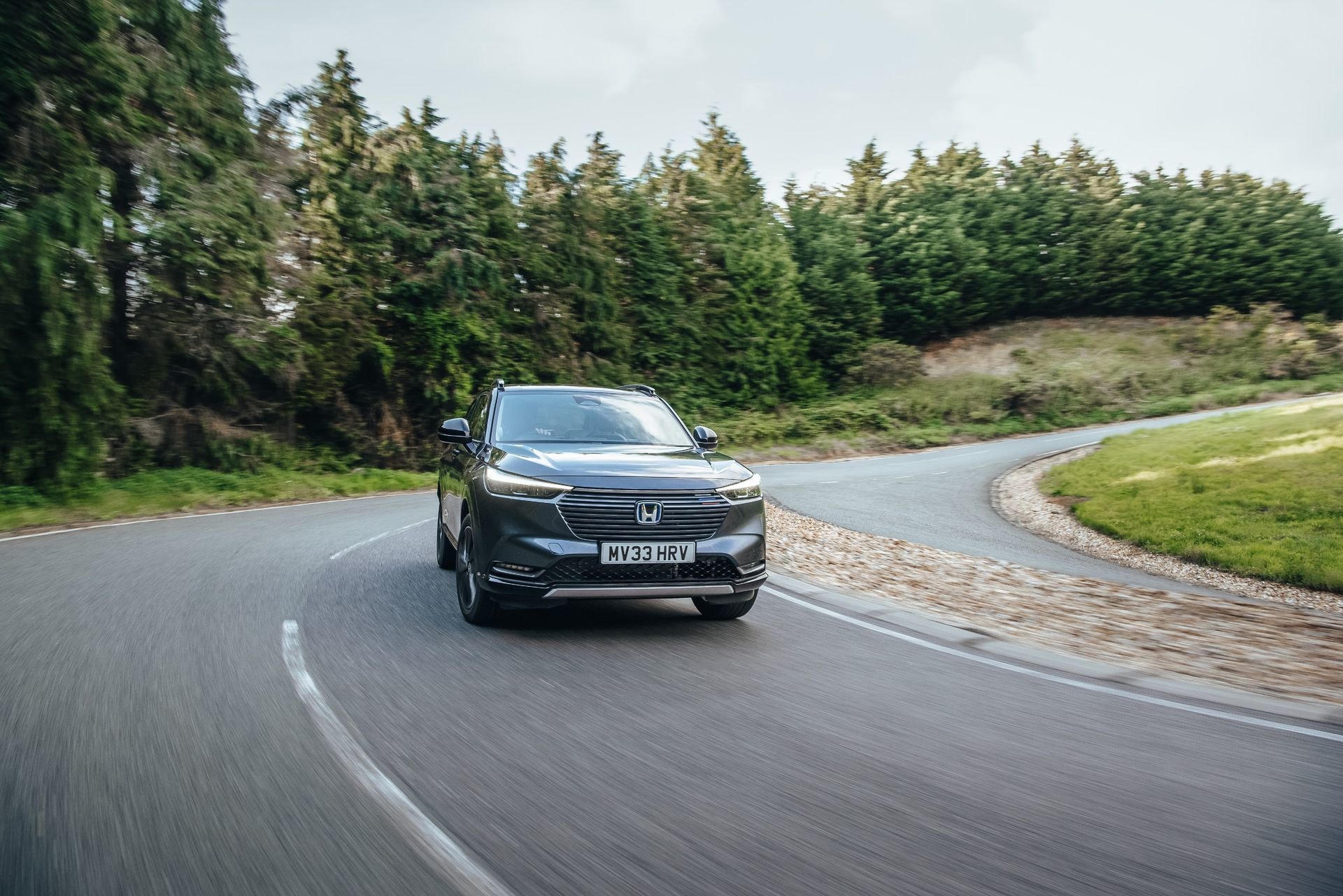 Toma dinámica del HR-V híbrido tomando una curva, vista delantera.
