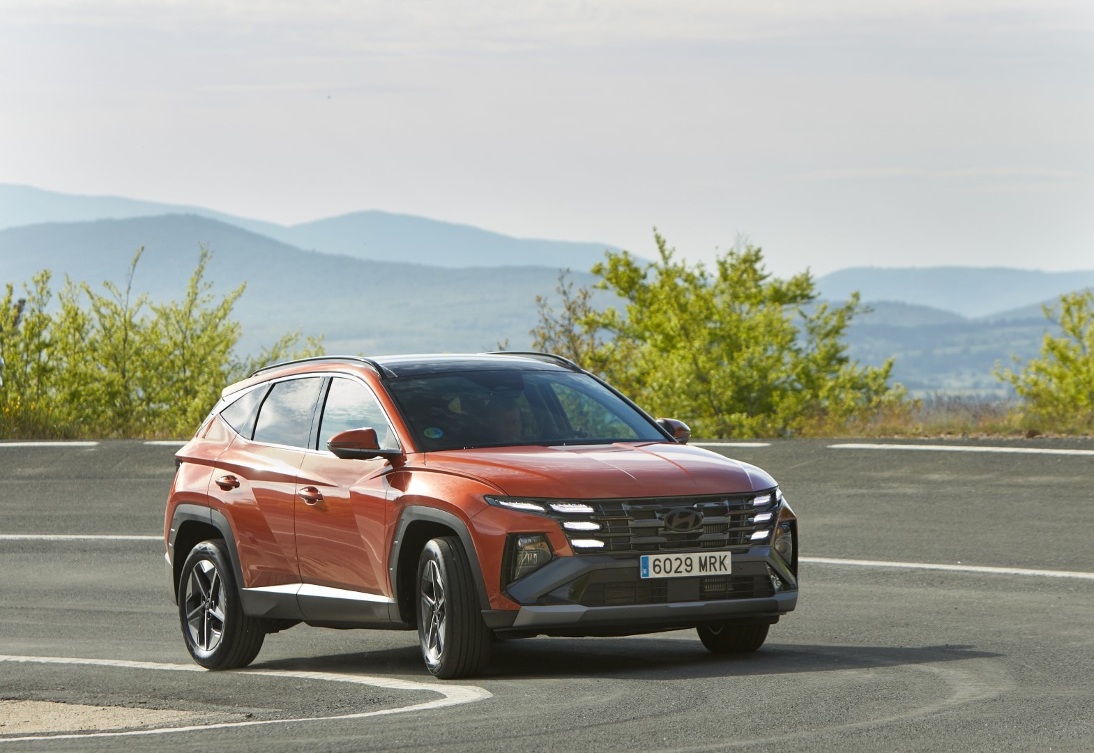 Vista dinámica del Tucson tomando una curva, mostrando su perfil lateral y frontal.