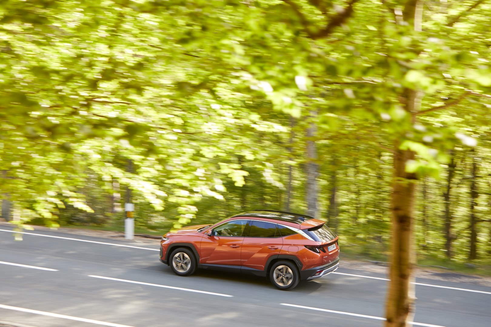 El Tucson en movimiento, mostrando su perfil lateral en un bosque