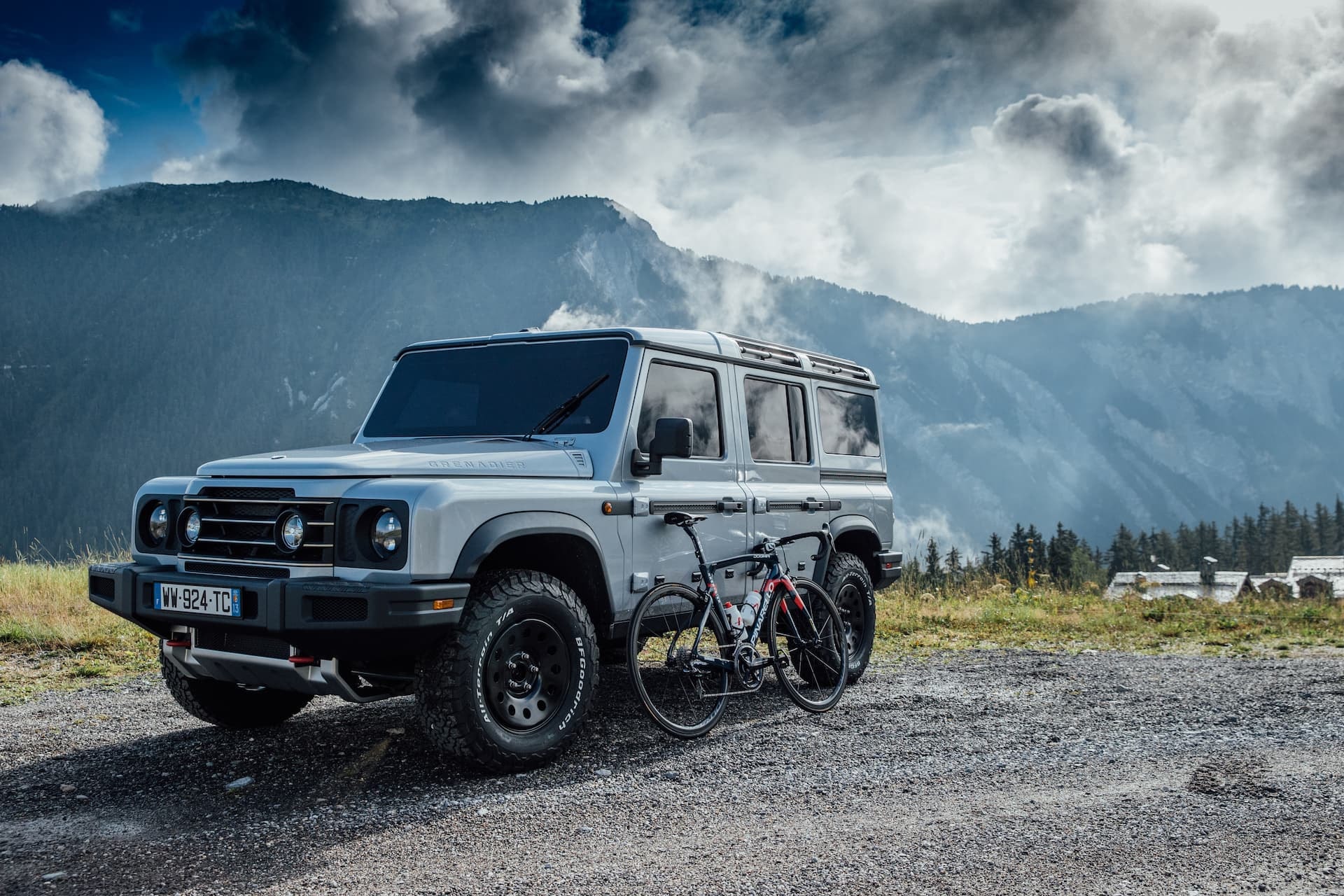 Ineos Grenadier aparcado en la montaña junto a una bicicleta, listo para la aventura.