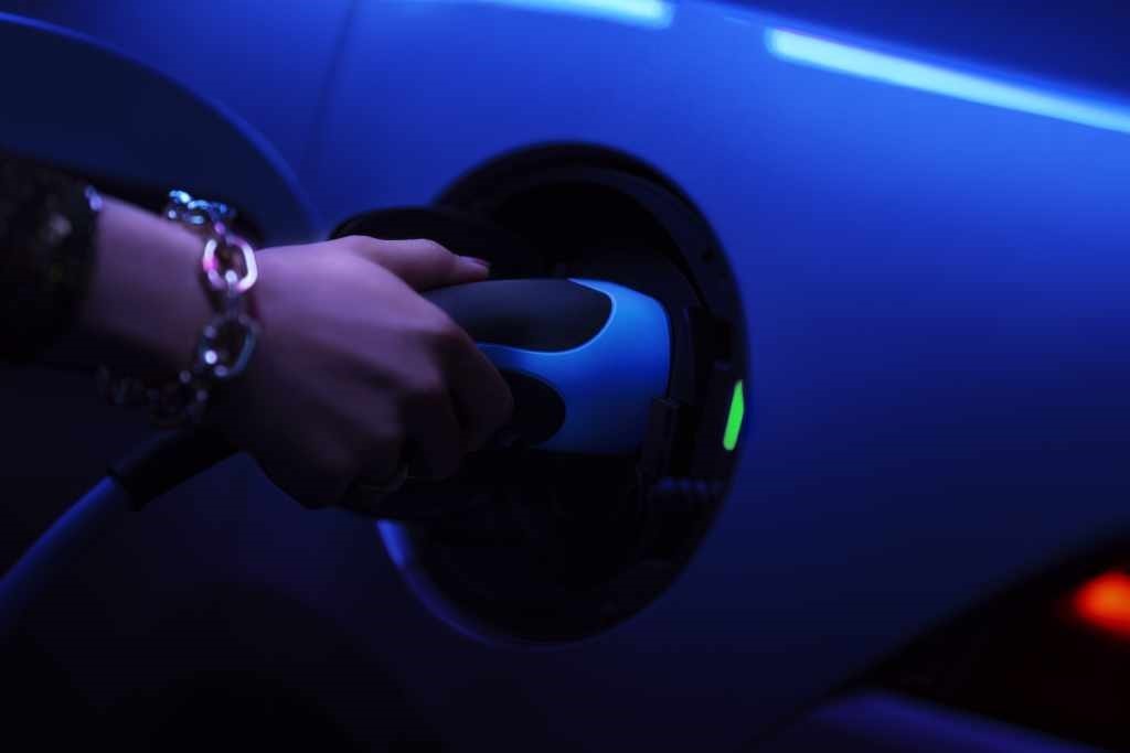 Mano conectando el enchufe de carga en el Jaguar E-Pace Híbrido, enfatizando su funcionalidad eléctrica.