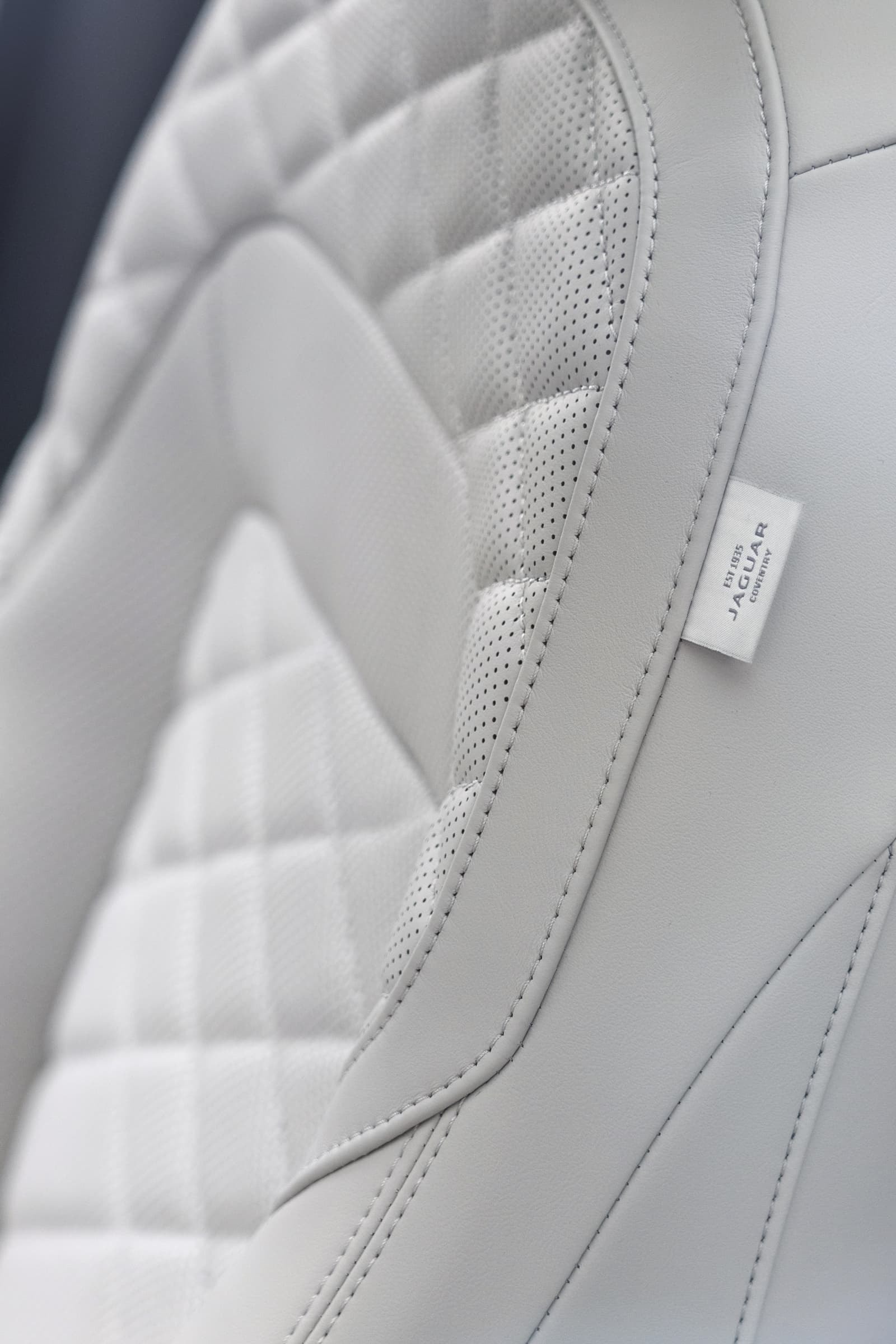 Detalle del asiento de cuero blanco con costuras en patrón tipo diamante.