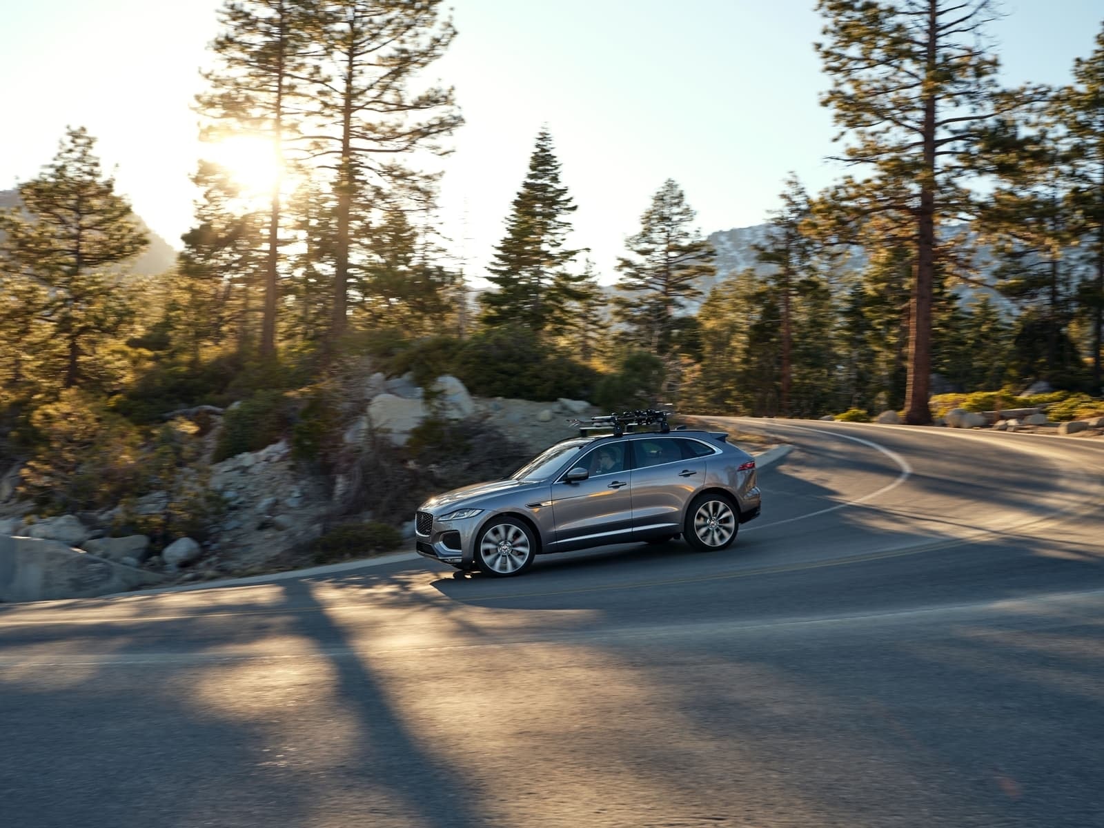 Vista lateral del Jaguar F-Pace mientras recorre una pintoresca carretera serpenteante.
