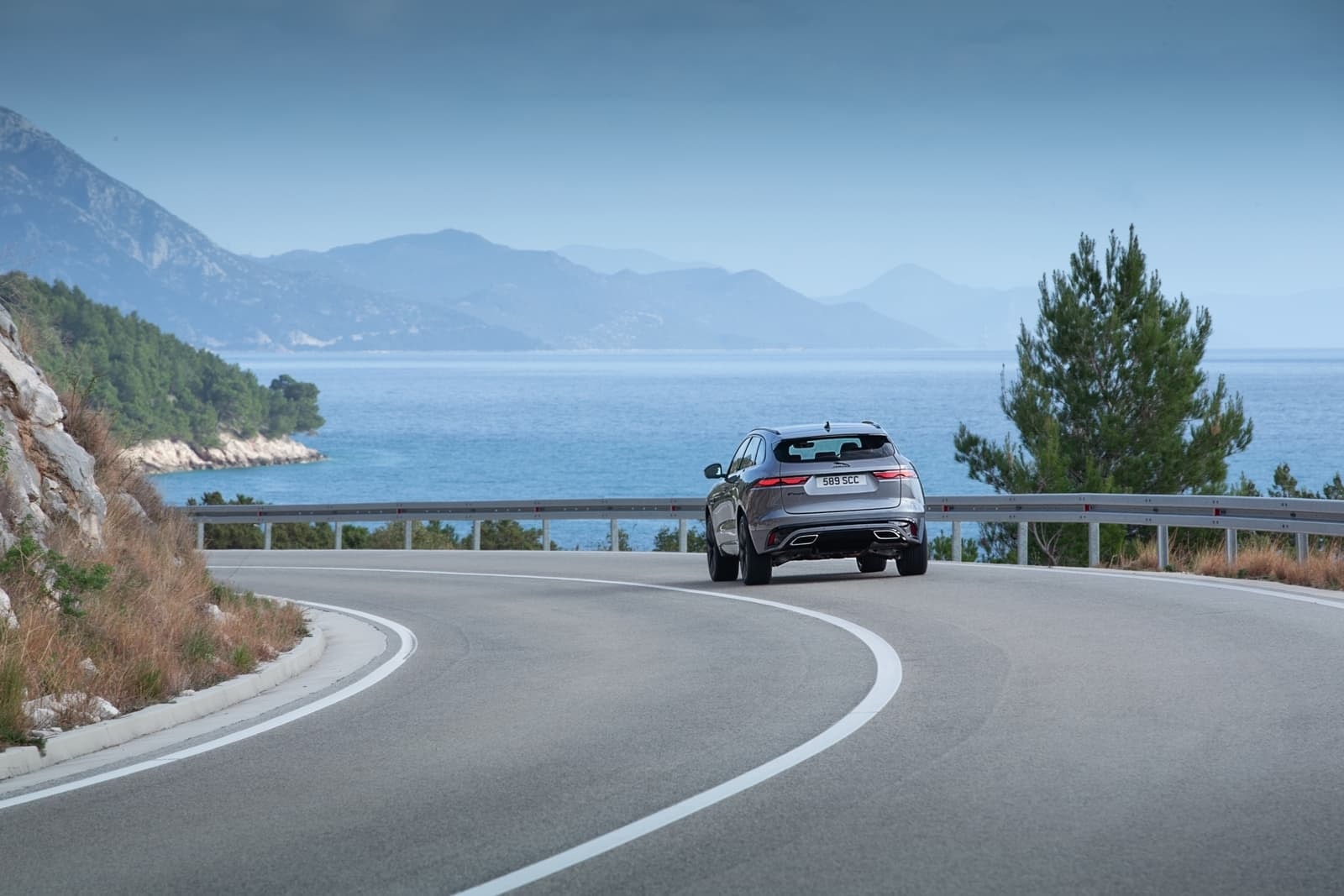 Vista trasera del Jaguar F-Pace recorriendo una ruta costera serpenteante.