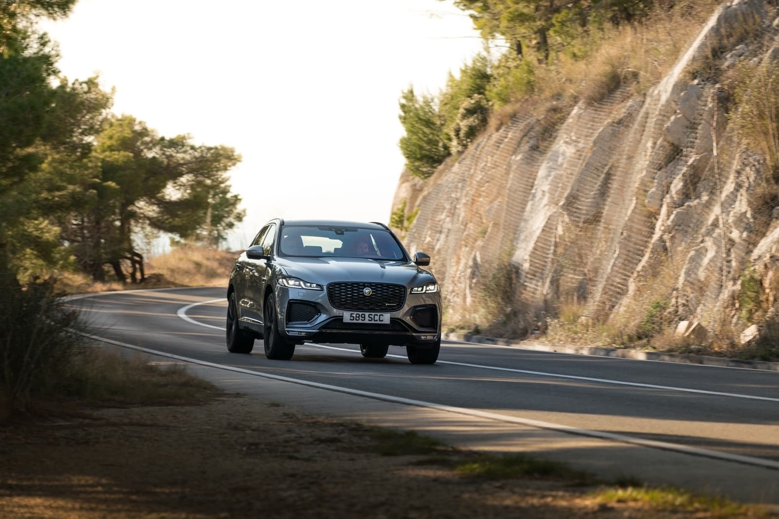 El F-Pace captado de frente mientras adelanta con presencia en un paraje montañoso.