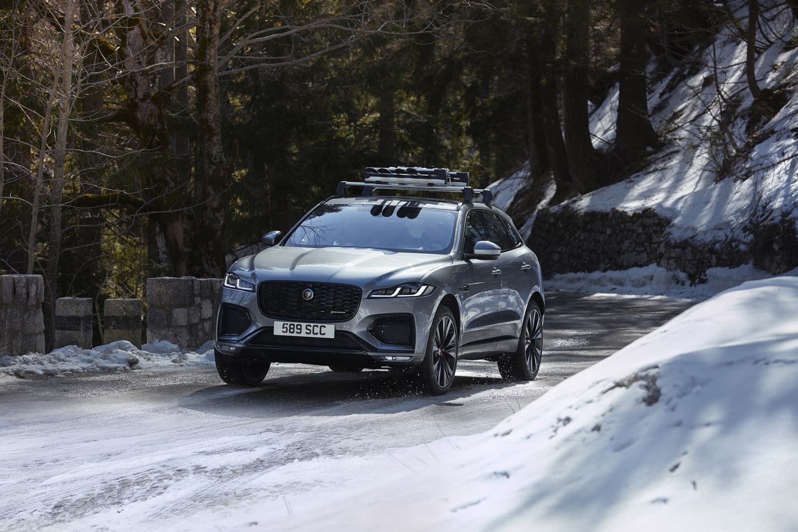 Imagen lateral con enfoque en el frontal del Jaguar F-Pace sobre la blanca estampa invernal.