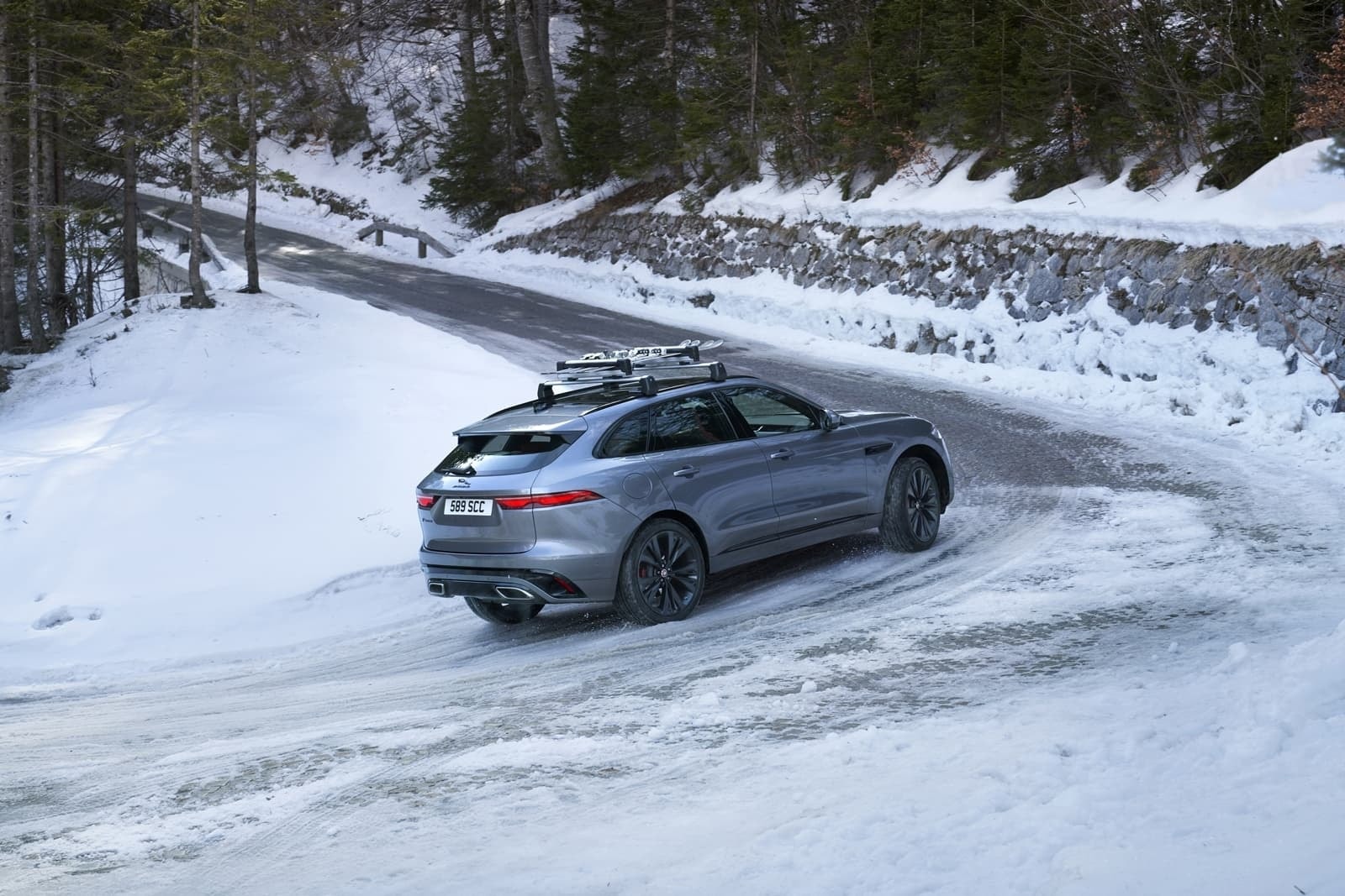 Perspectiva lateral del Jaguar F-Pace rodando sobre nieve, exhibiendo líneas y llantas.
