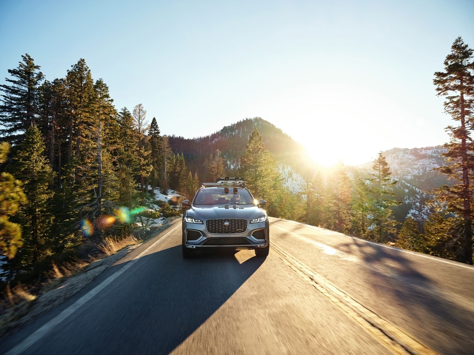 Imagen frontal del Jaguar F-Pace con el sol de frente en carretera.