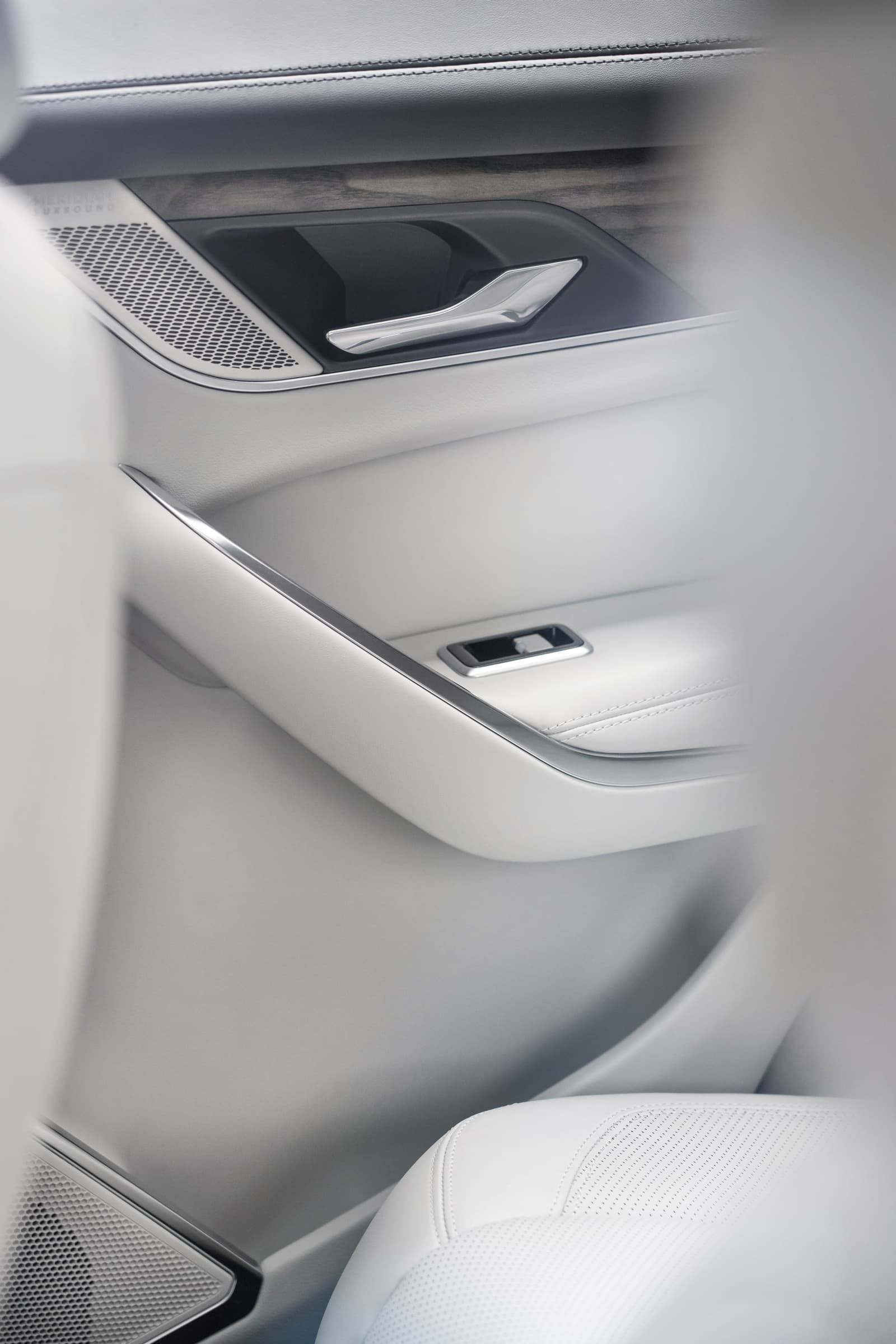 Detalle del panel de puerta con inserciones de aluminio y cuero blanco.