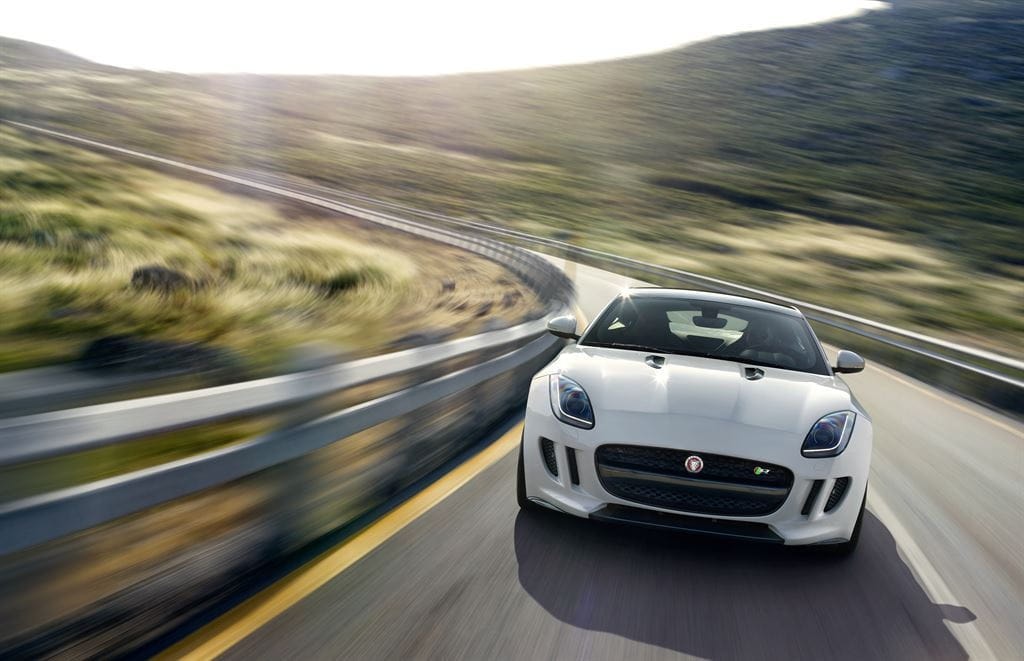 Vista delantera de un Jaguar F-Type Coupé en plena carrera en una carretera.