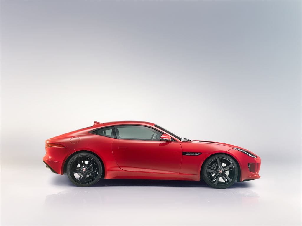 Imagen del Jaguar F-Type Coupé con la puerta abierta en carretera.