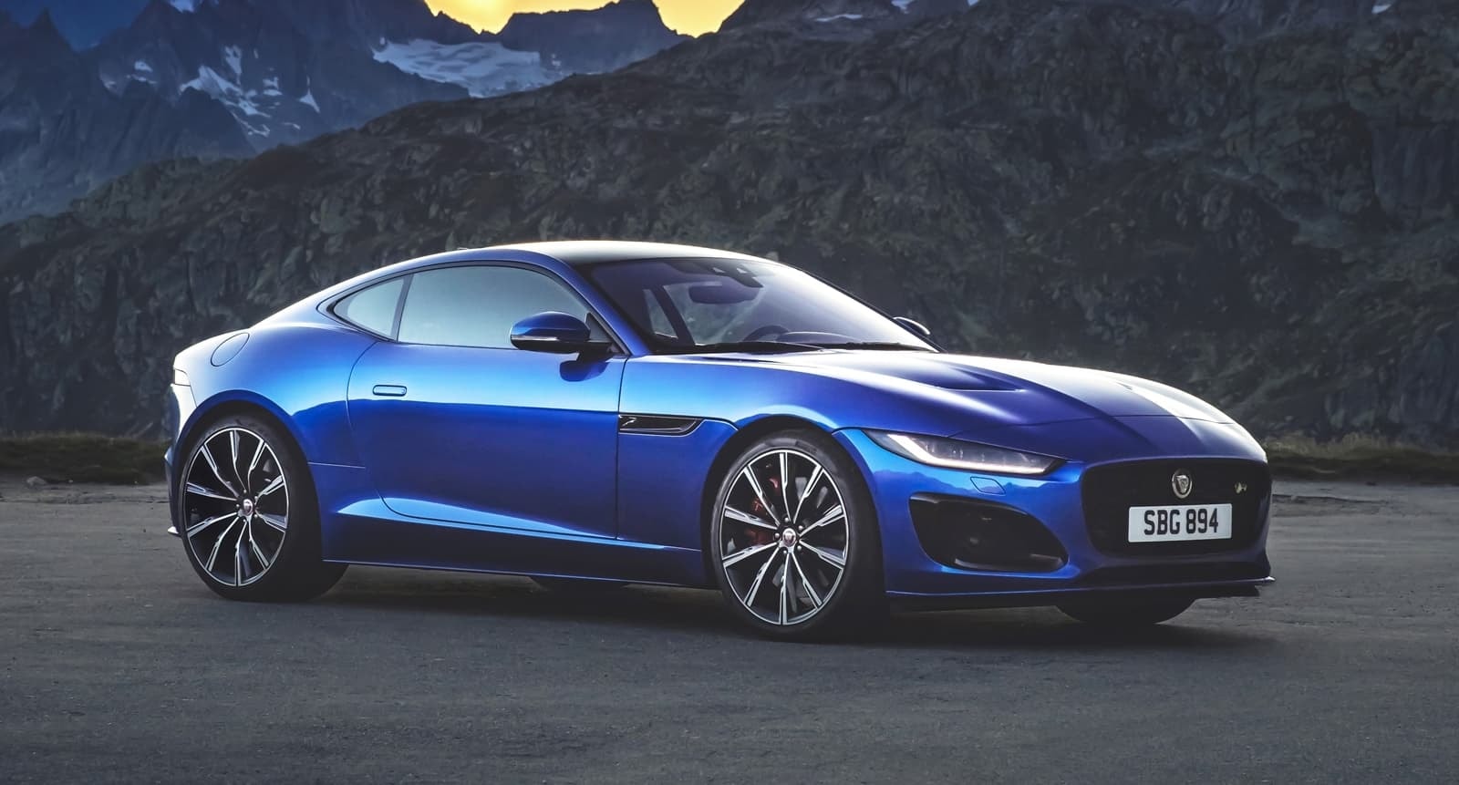 Lateral completo del Jaguar F-Type, perfectamente enmarcado contra un majestuoso telón de montaña.