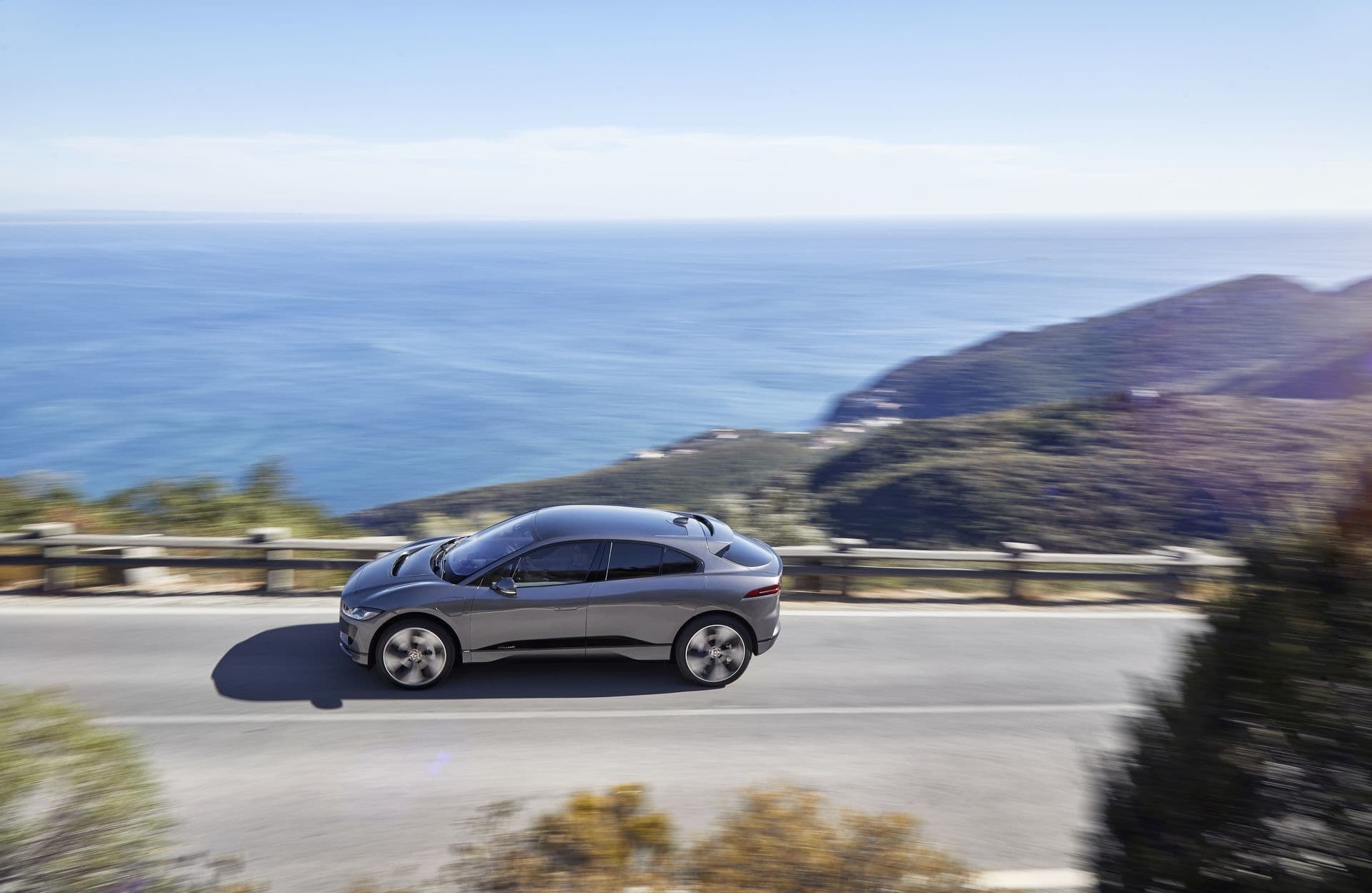 Imagen dinámica del Jaguar I-Pace en carretera costera durante el día.