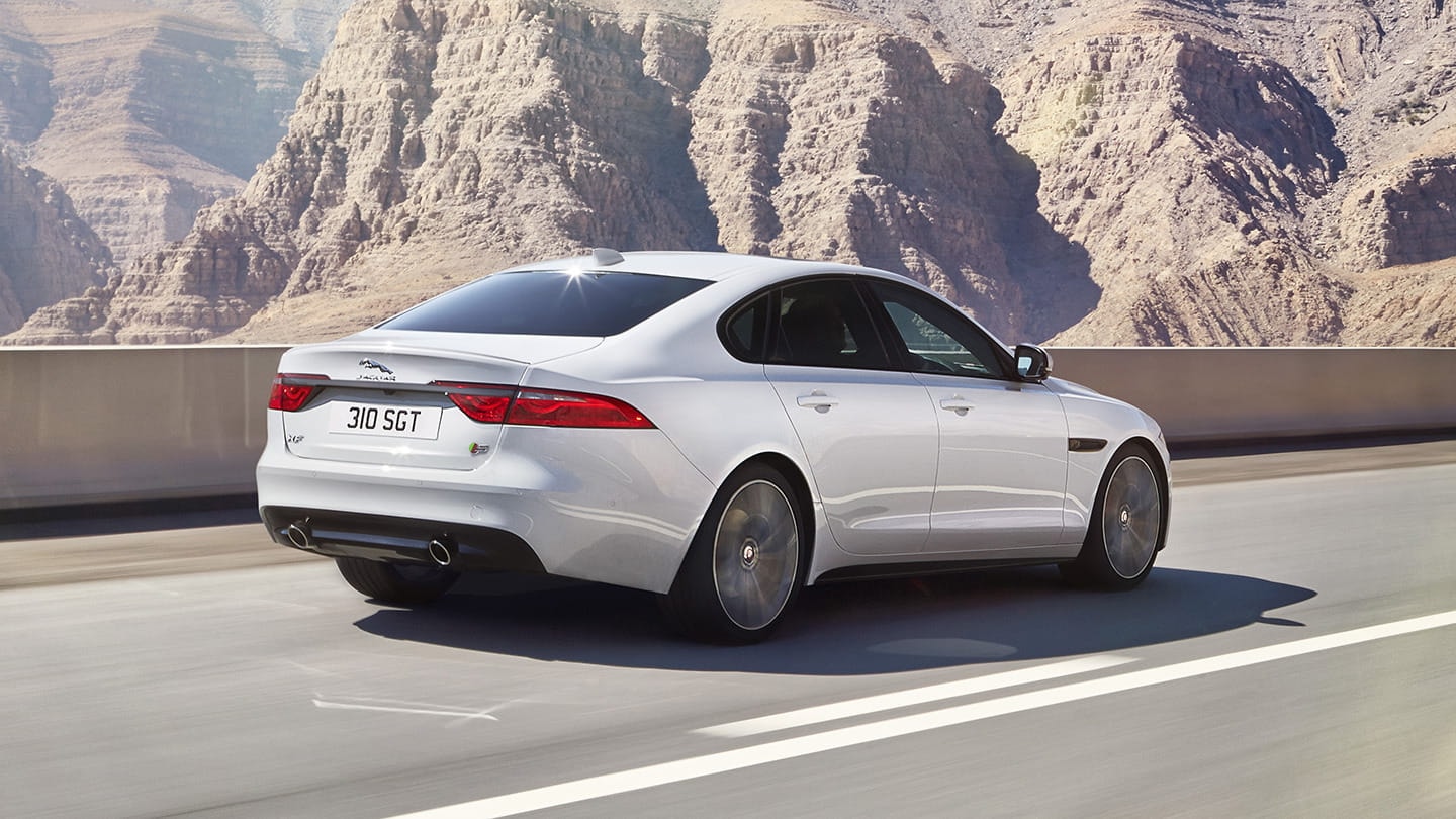 Toma trasera del Jaguar XF en carretera, mostrando la elegancia y deportividad de su diseño.