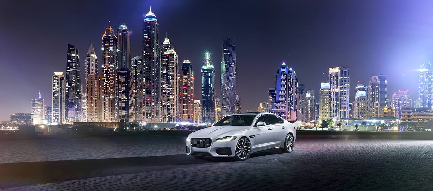 El Jaguar XF posando con el skyline nocturno, ilustrando su prestancia urbana.
