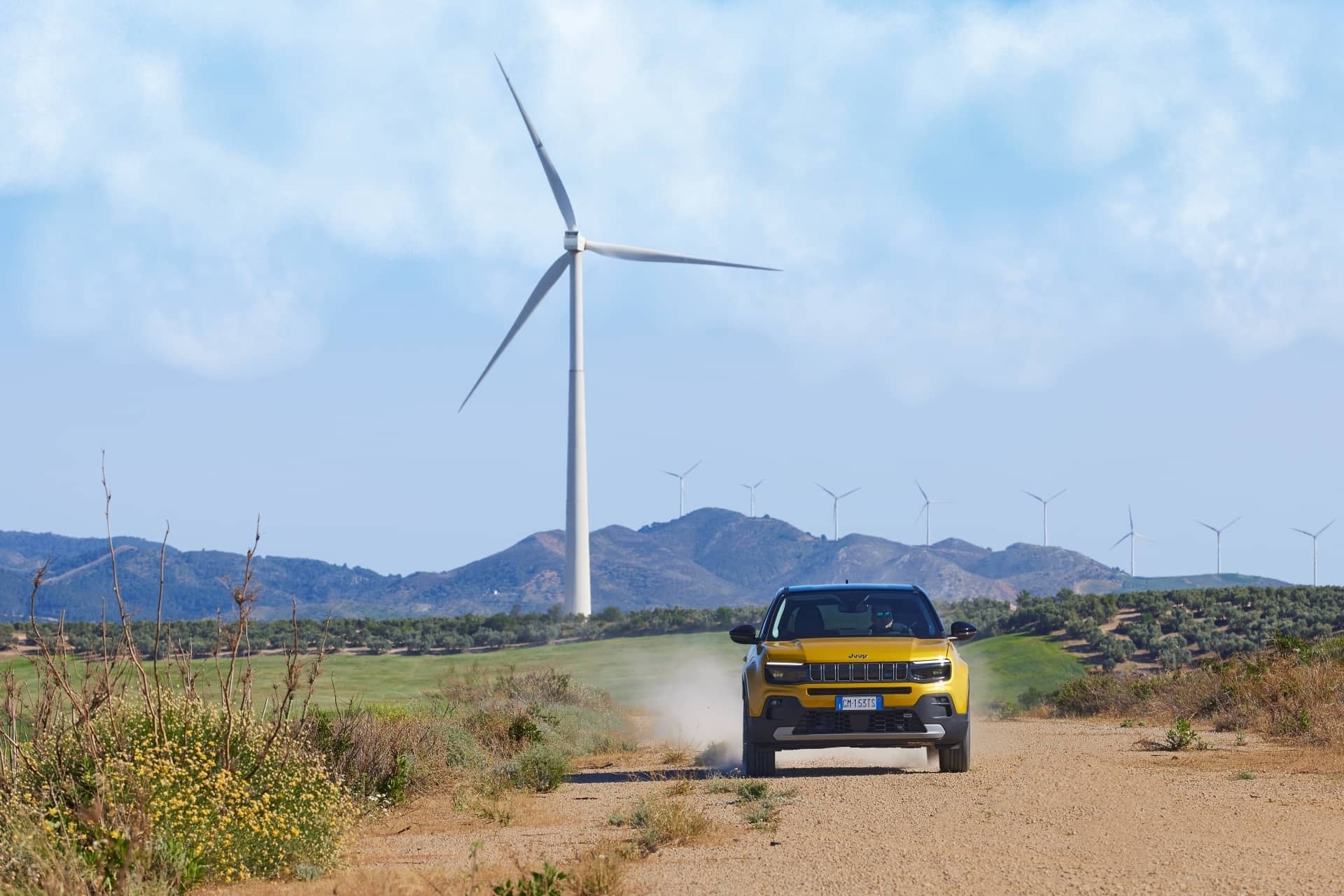 Jeep Avenger delante de molinos eólicos, destacando su carácter aventurero.