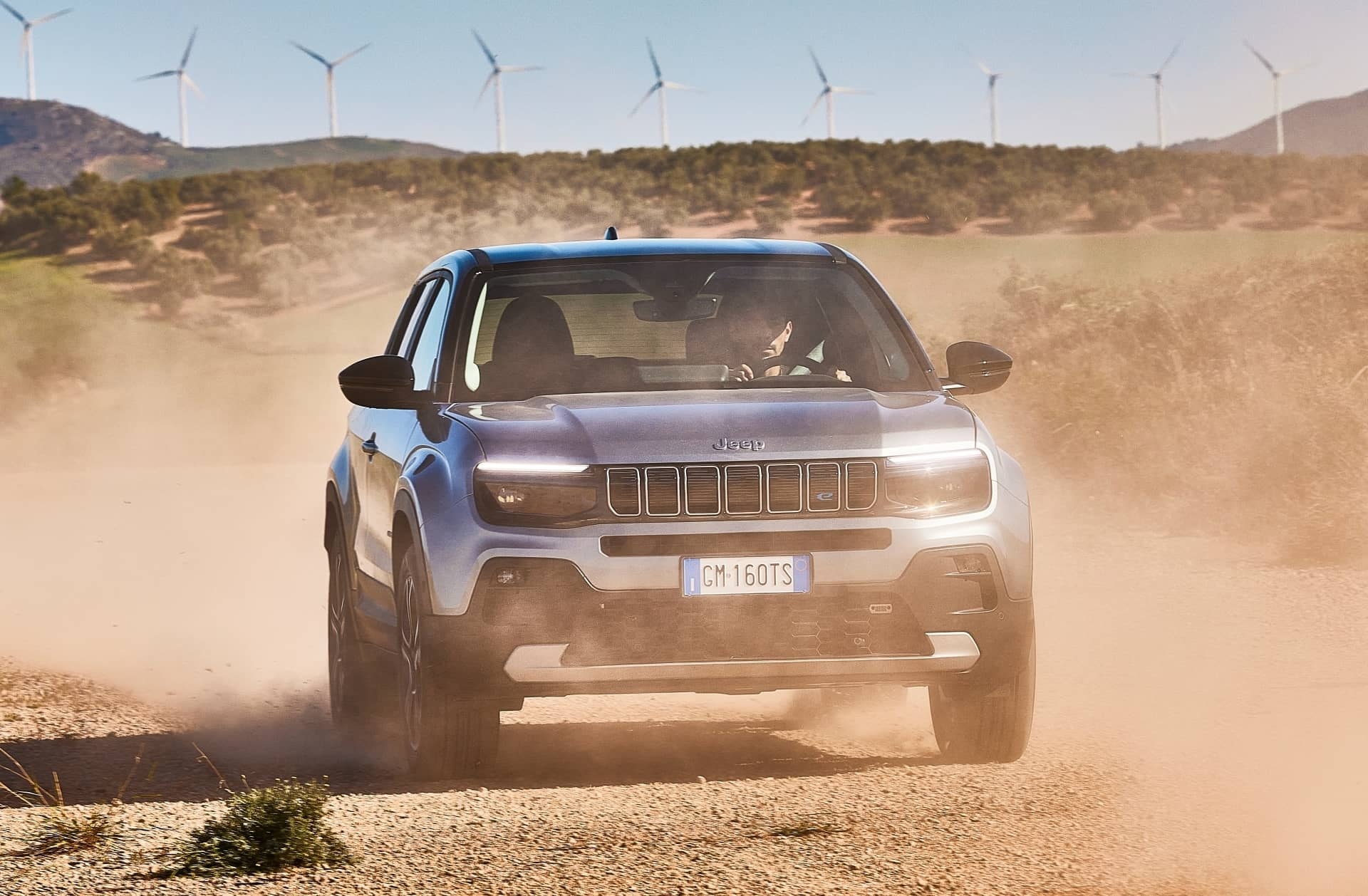 Vista frontal del Jeep Avenger destacando su parrilla en un entorno desértico.