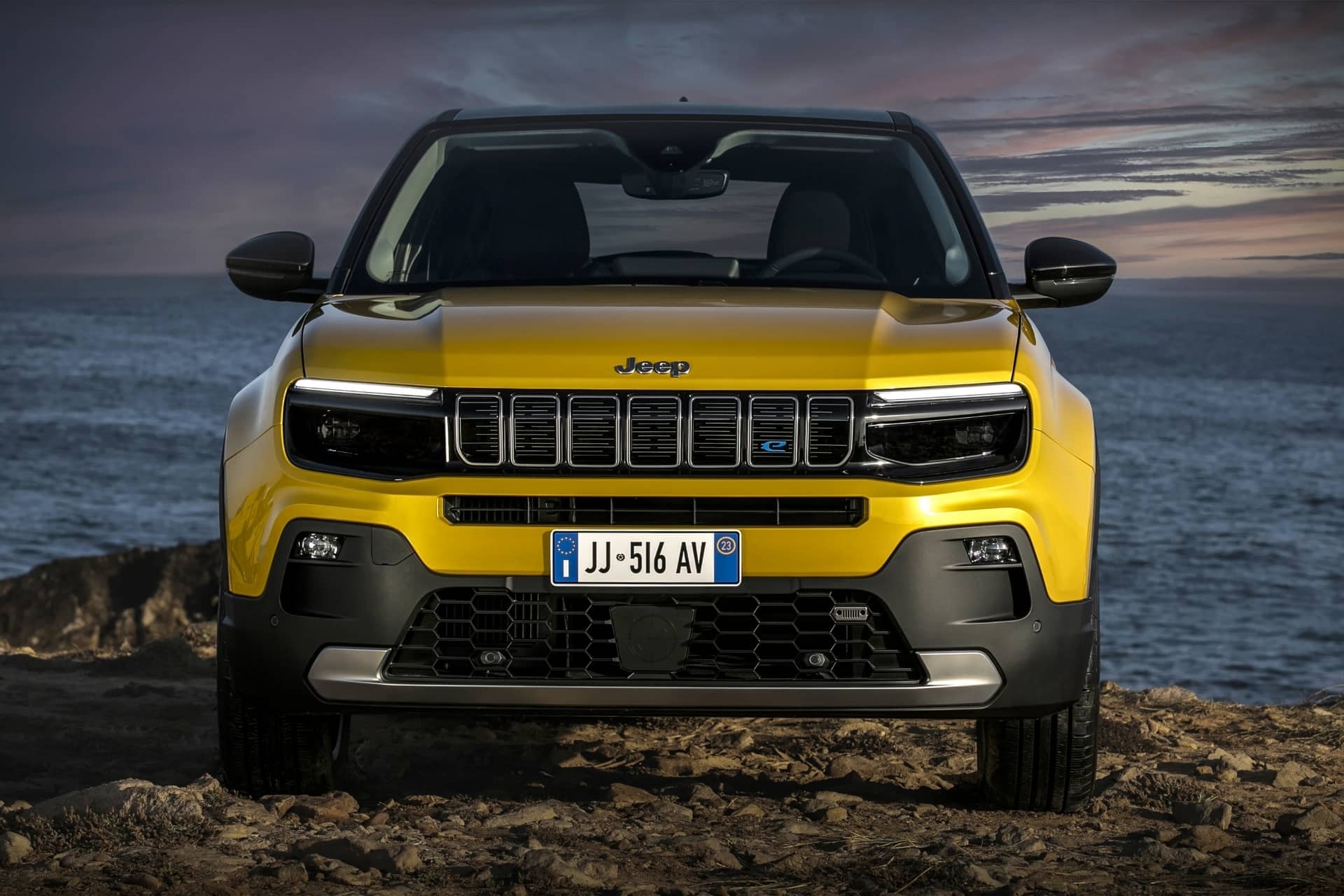 Vista frontal del Jeep Avenger con fondo de playa al atardecer