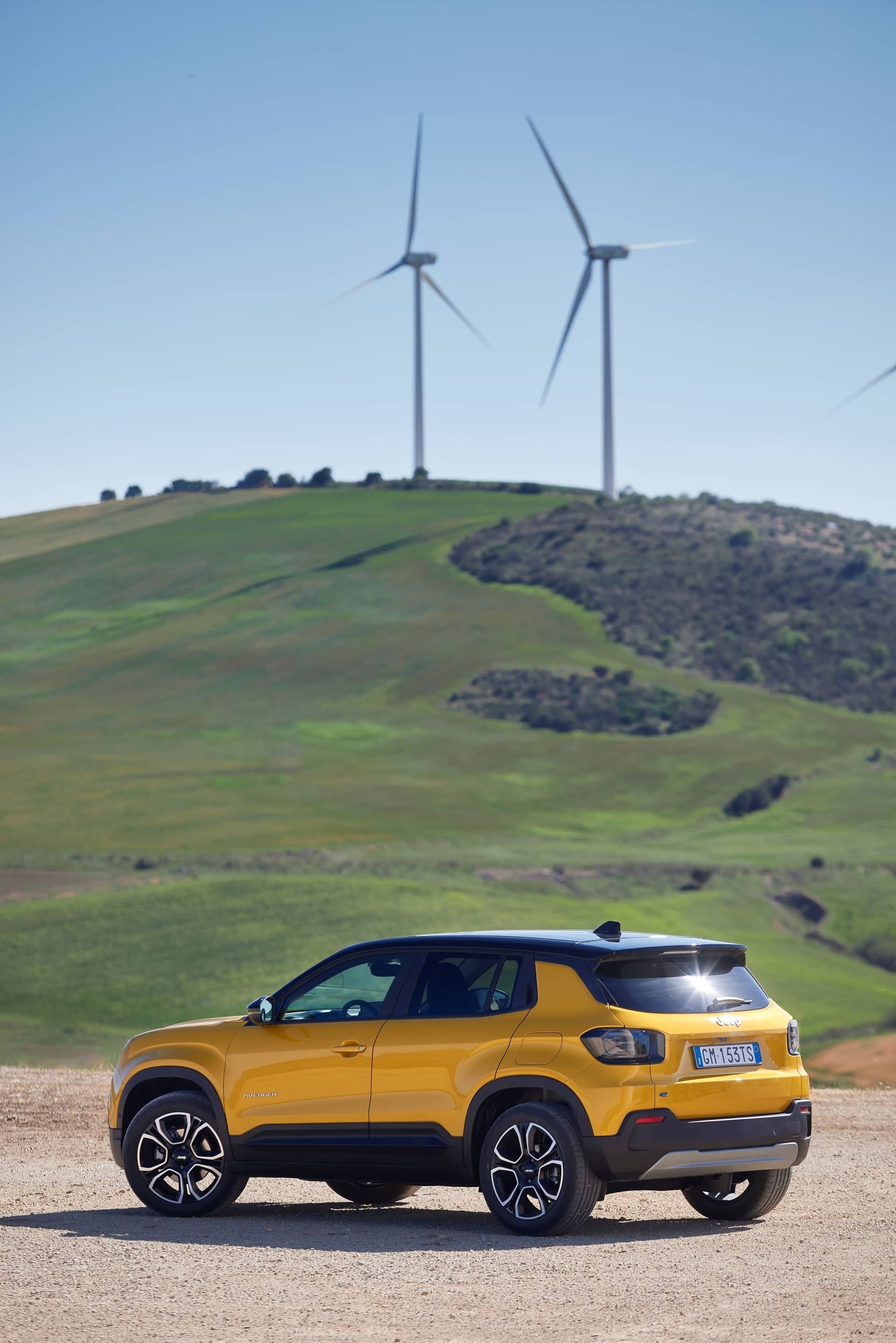 Muestra dinámica del Jeep Avenger en paisaje con molinos de viento.