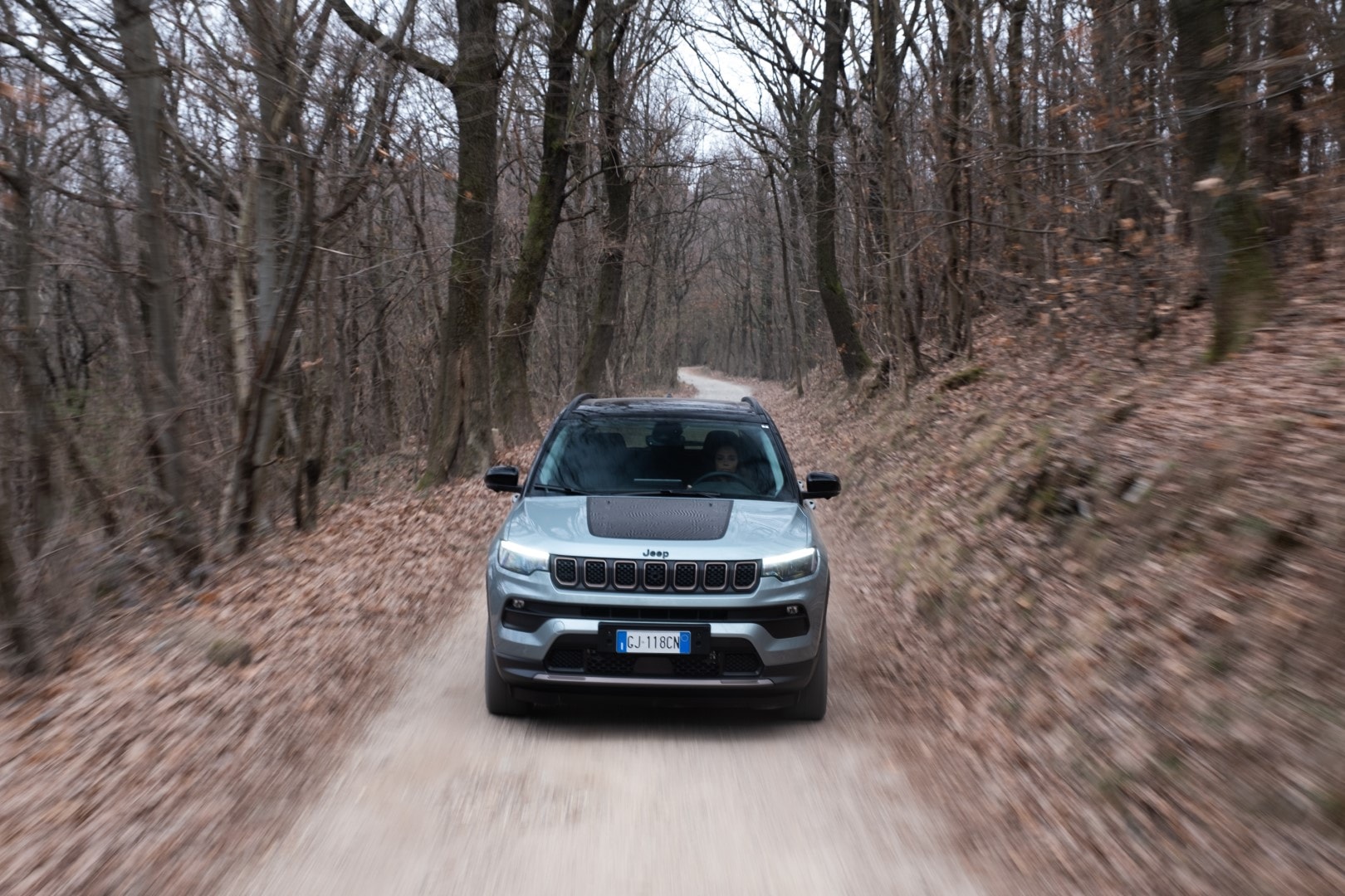 Perfil del Jeep Compass Híbrido demostrando su capacidad off-road en un bosque.