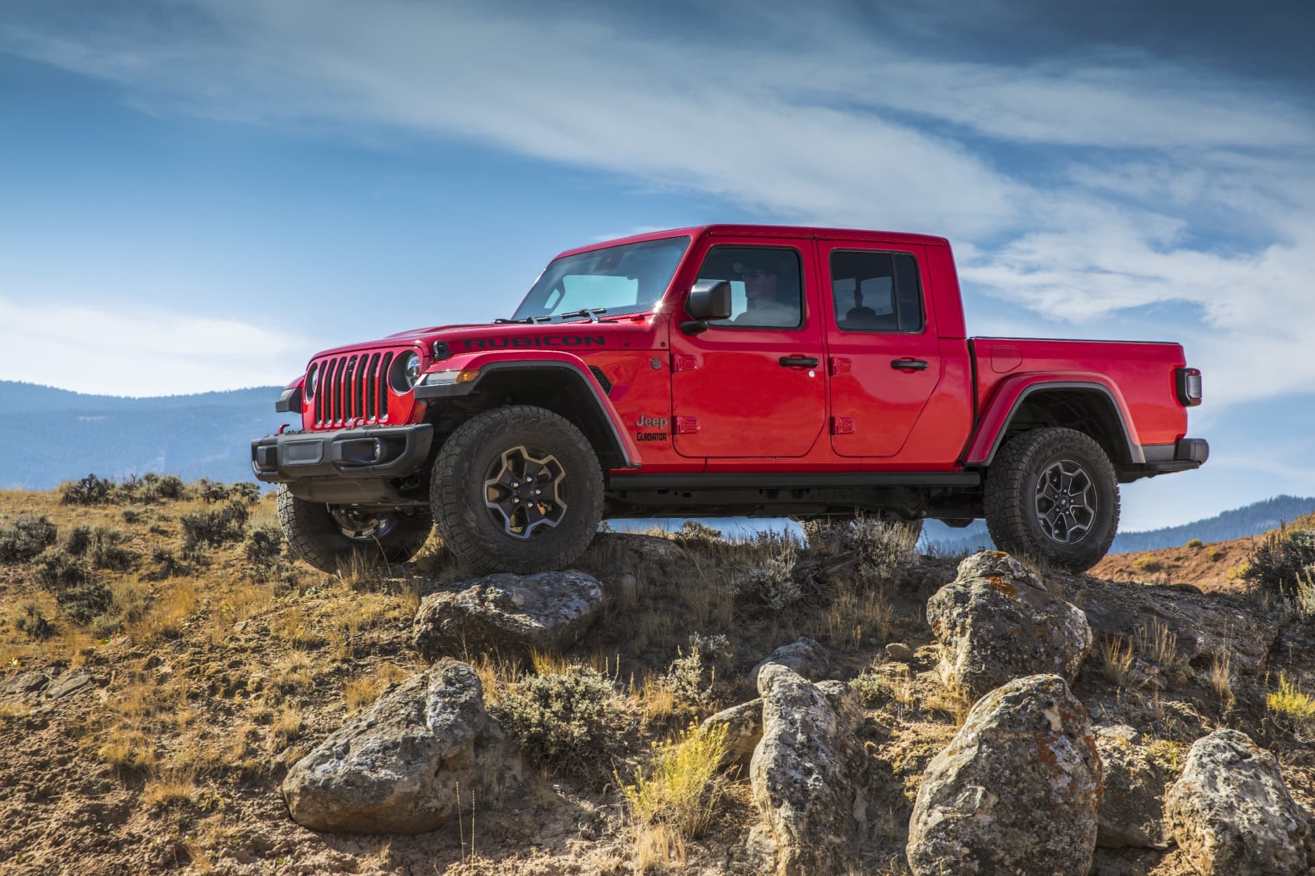 Jeep Gladiator rojo superando obstáculos en terreno rocoso