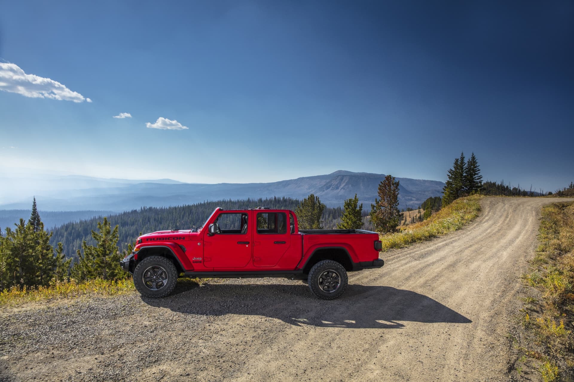 Vista lateral del Jeep Gladiator en camino de montaña, enfatizando su perfil aventurero.
