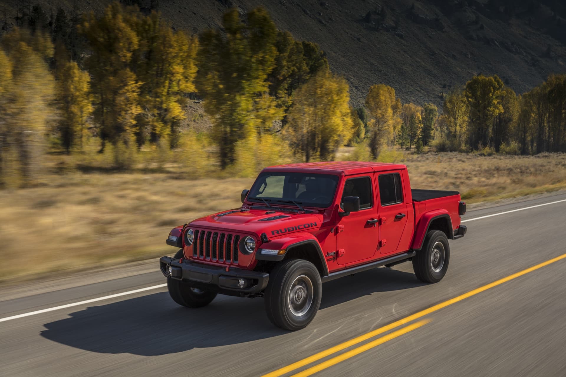 Jeep Gladiator en rojo mostrando su perfil en movimiento.