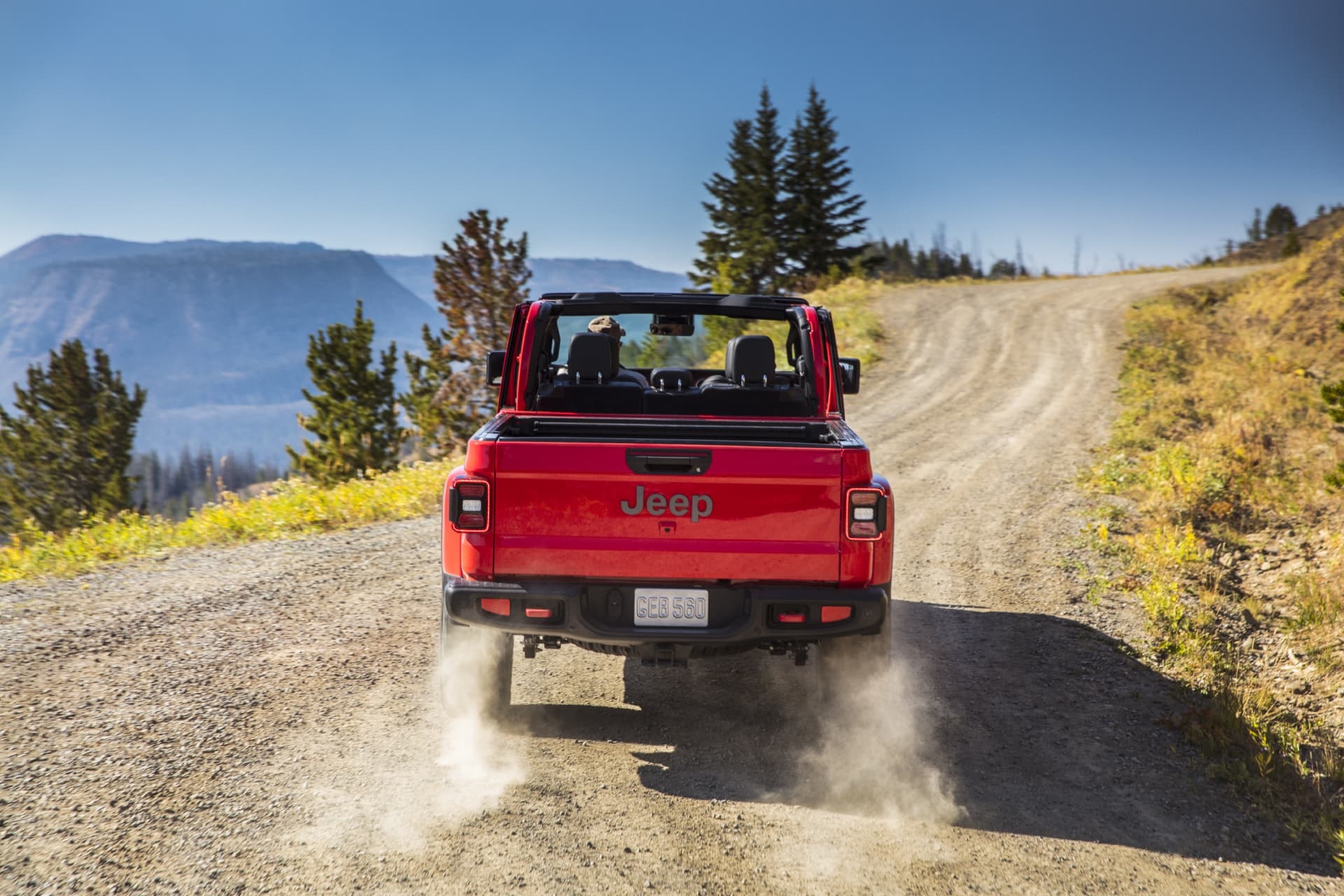 Perspectiva trasera de un Jeep Gladiator rojo en una carretera de montaña.