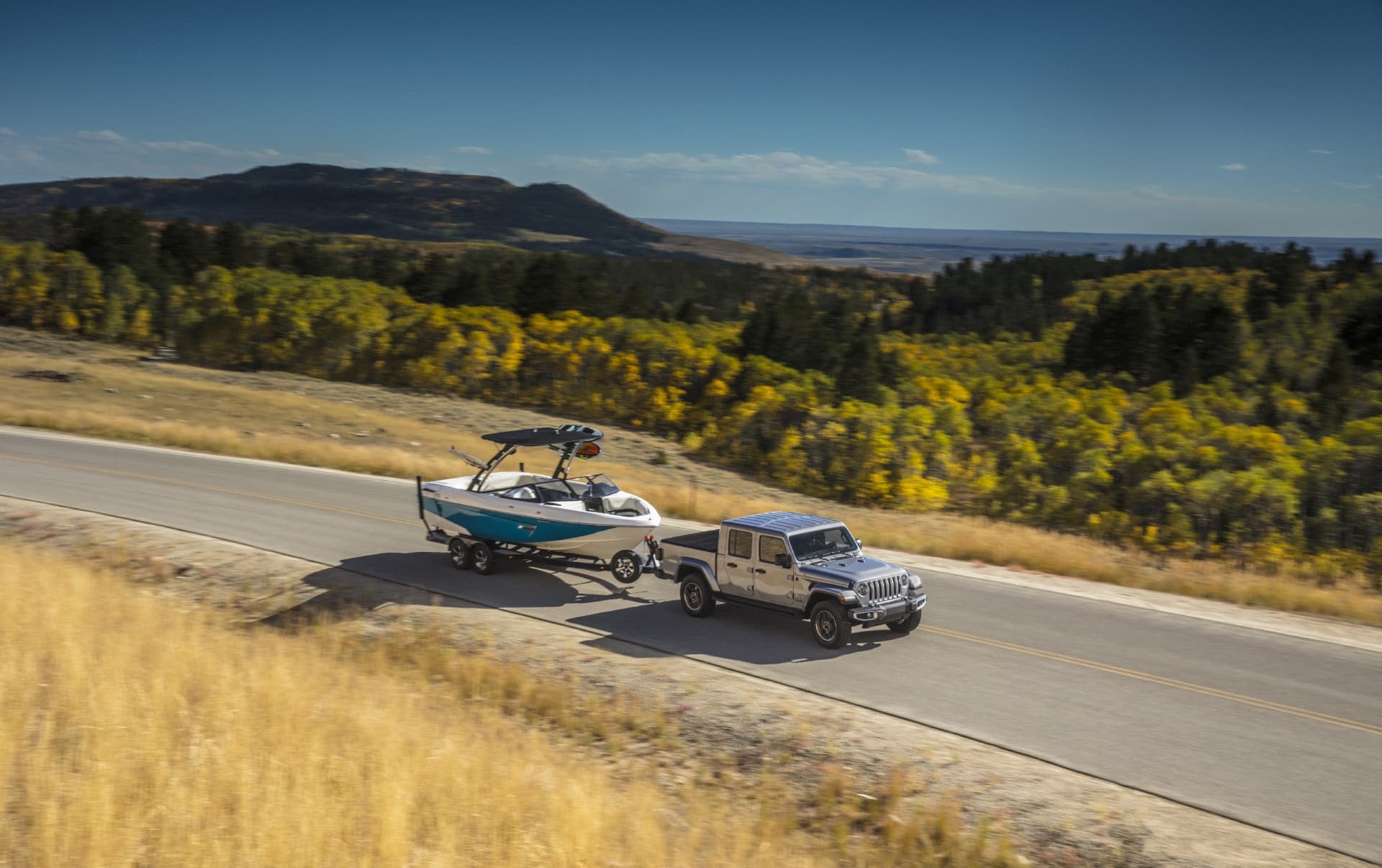 Jeep Gladiator remolcando embarcación en ruta escénica, funcionalidad en movimiento