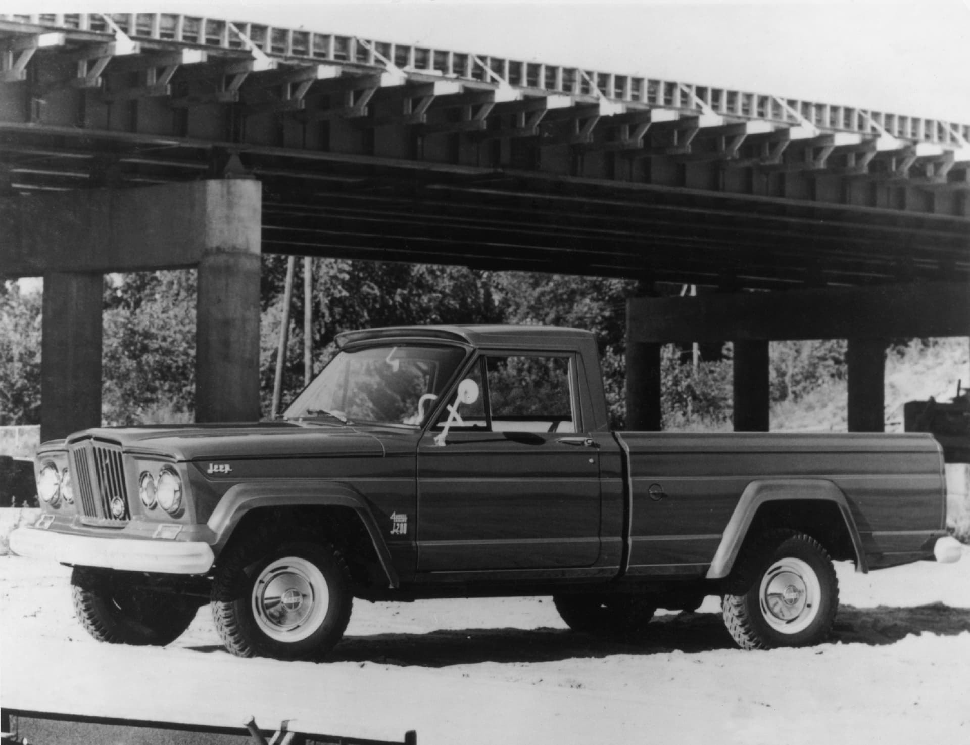 Clásico Jeep Gladiator en blanco y negro bajo un puente