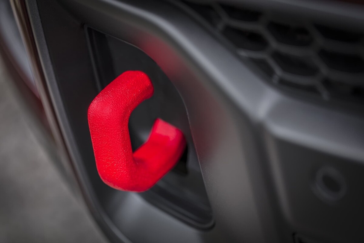 Gancho de remolque delantero en rojo, detalle funcional y estético. Gancho de remolque delantero en rojo, detalle funcional y estético.
