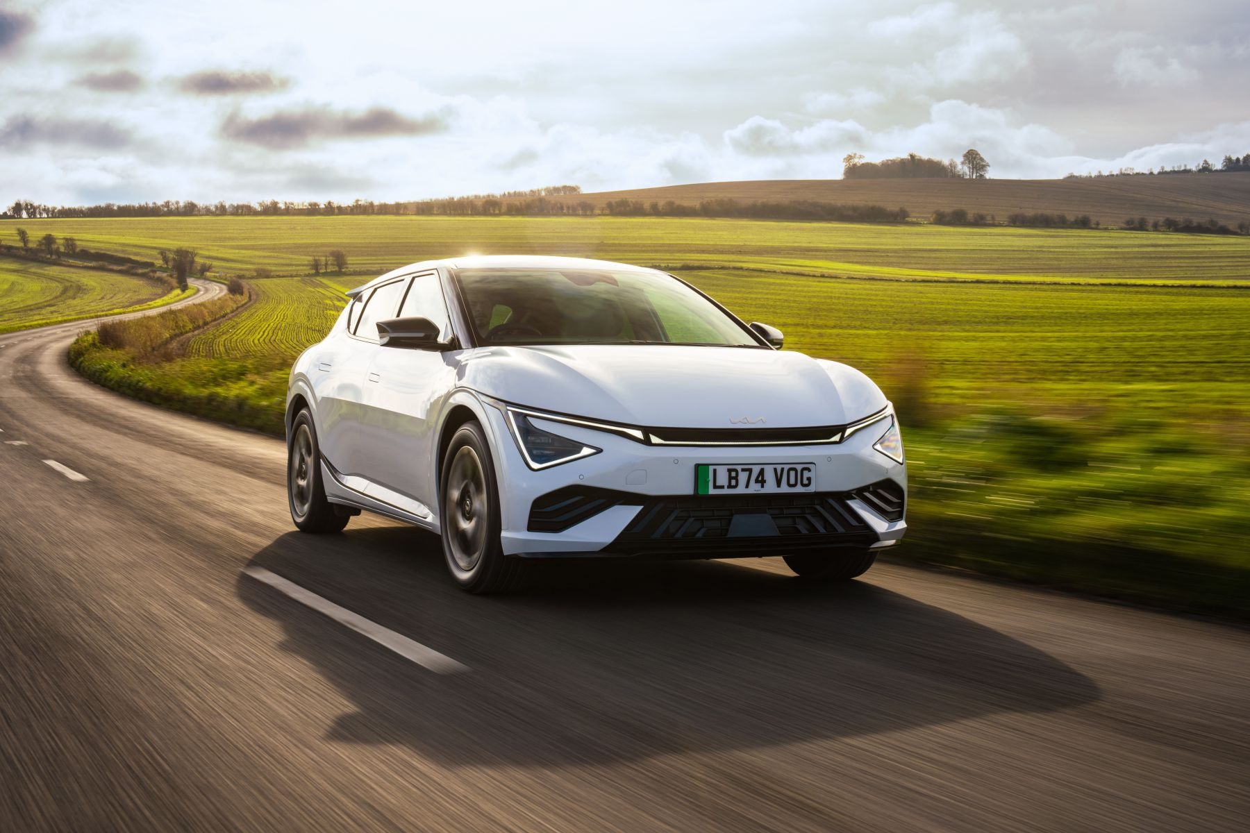 Vista trasera del Kia EV6 en la carretera, armonizando con el paisaje.