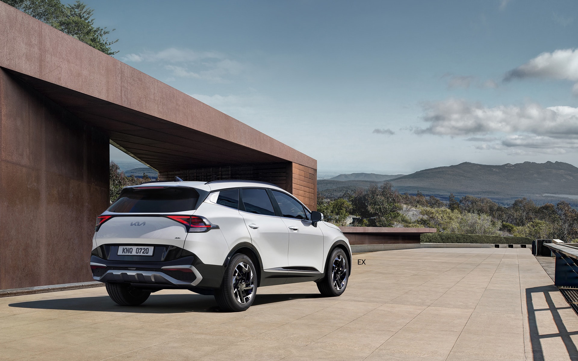 Vista trasera del Kia Sportage híbrido aparcado en un entorno moderno.