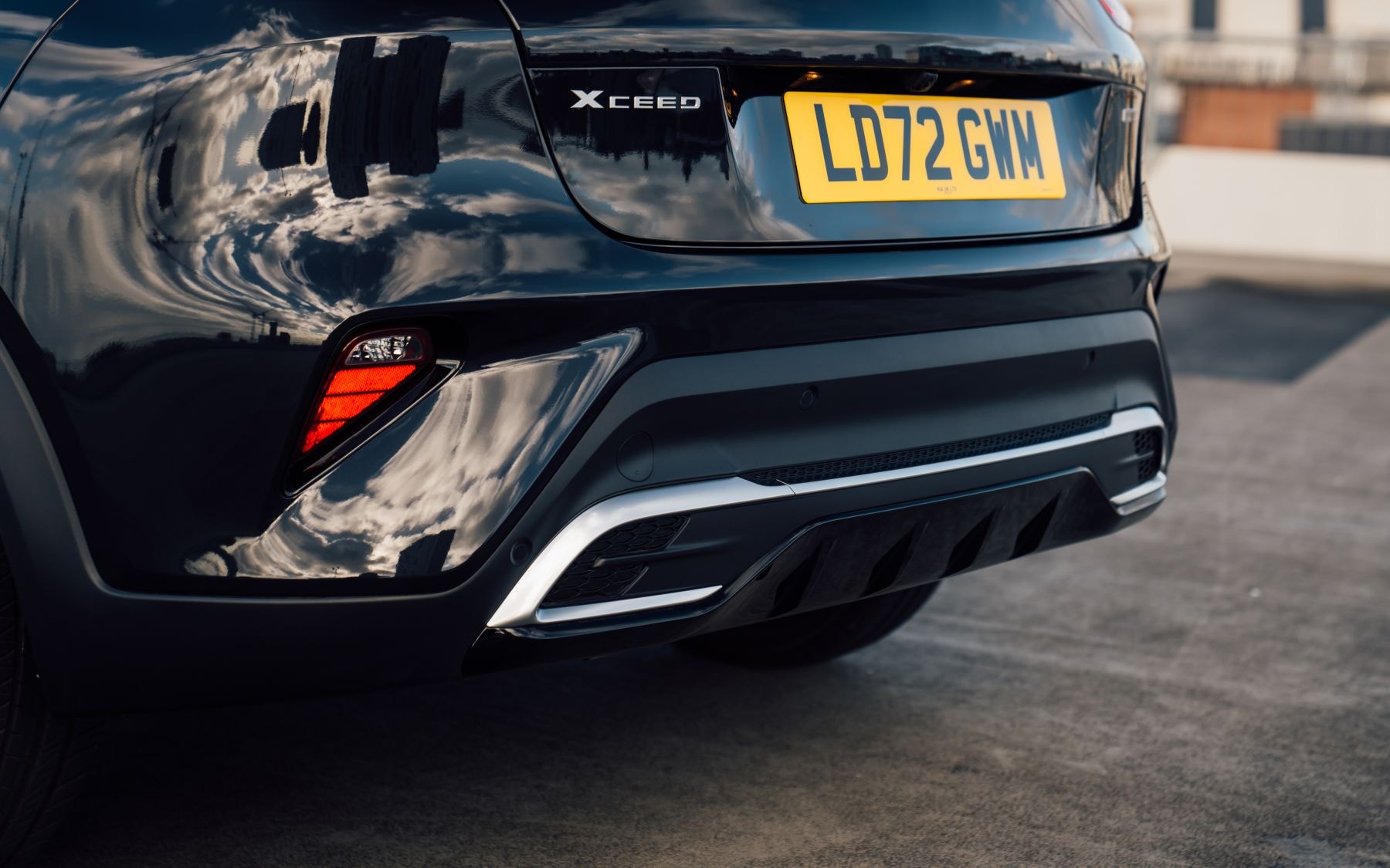 Perfil lateral del Kia Xceed Híbrido estacionado junto a un muro.