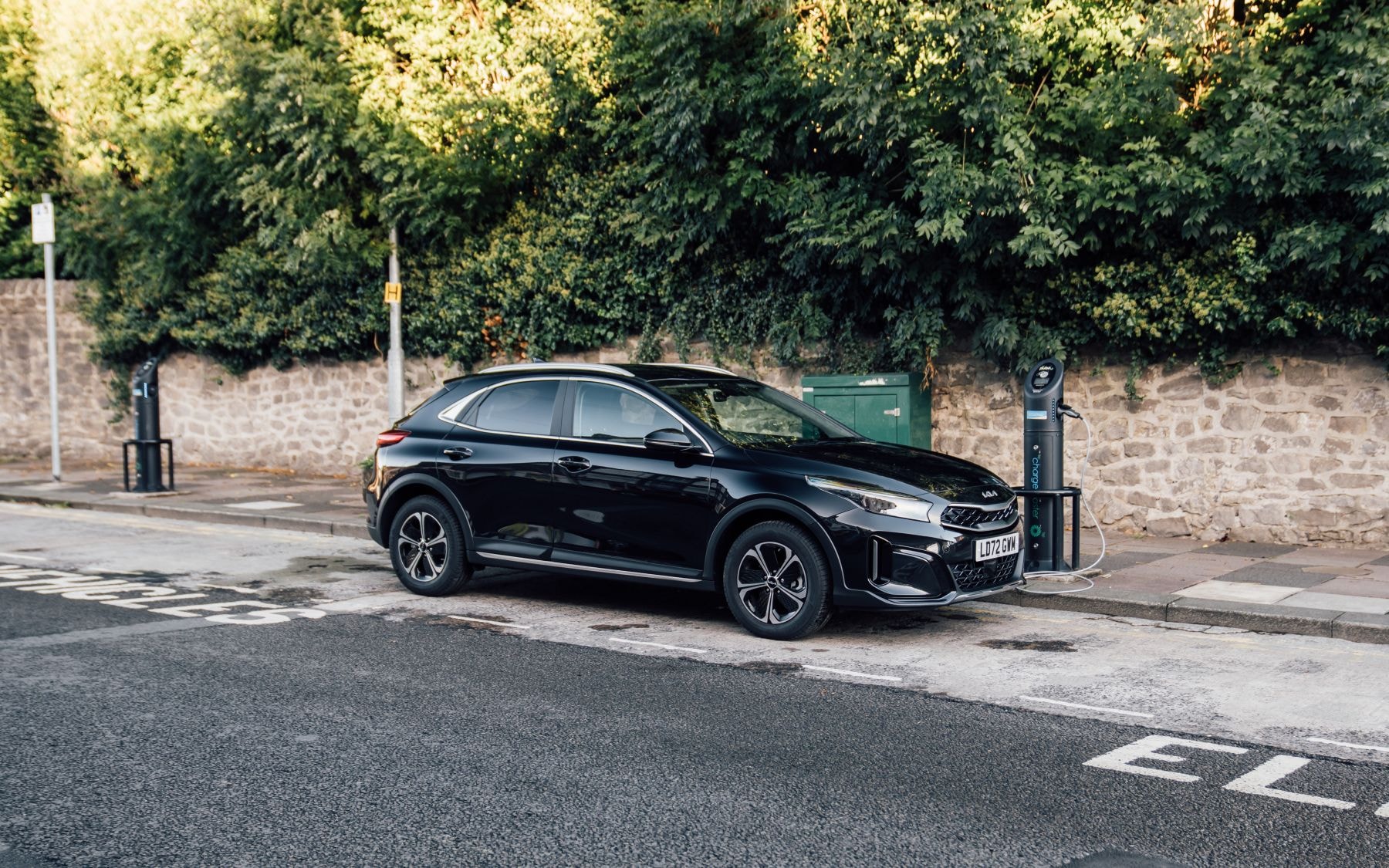 Kia Xceed Híbrido en movimiento por una carretera arbolada.
