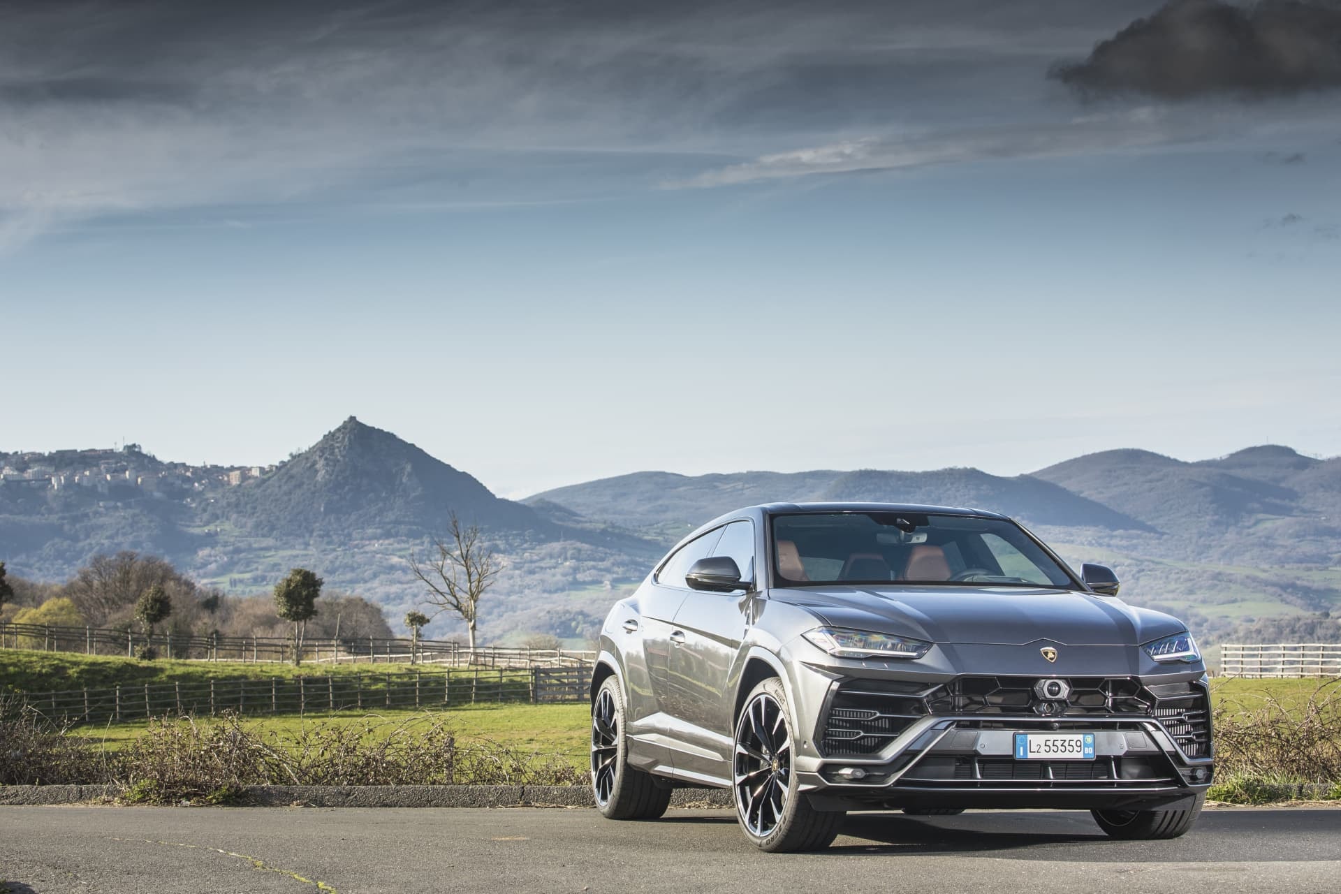 Lamborghini Urus gris con un fondo montañoso, mostrando un perfil elegante y deportivo.