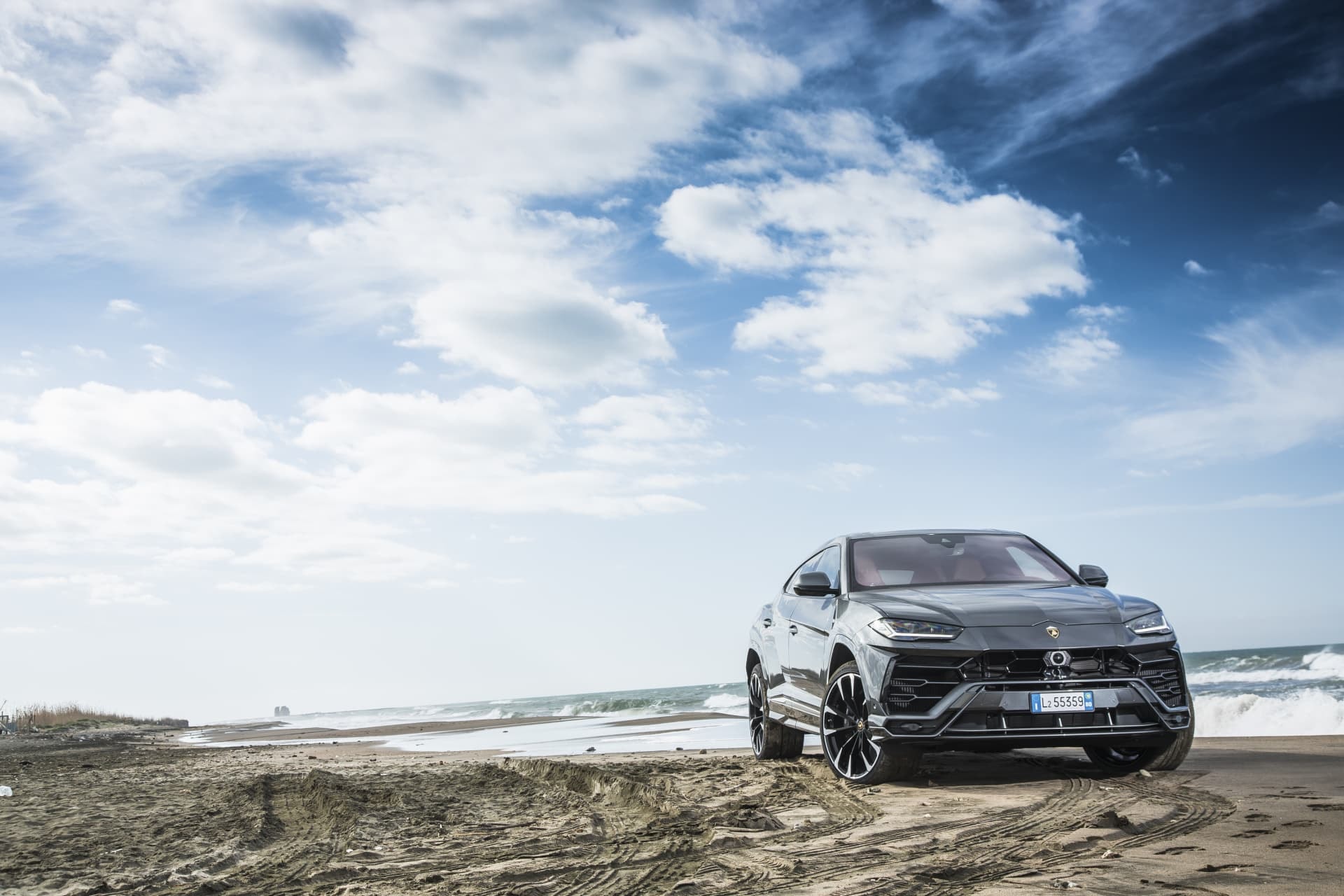 Vista trasera del Lamborghini Urus aparcado frente a una playa.