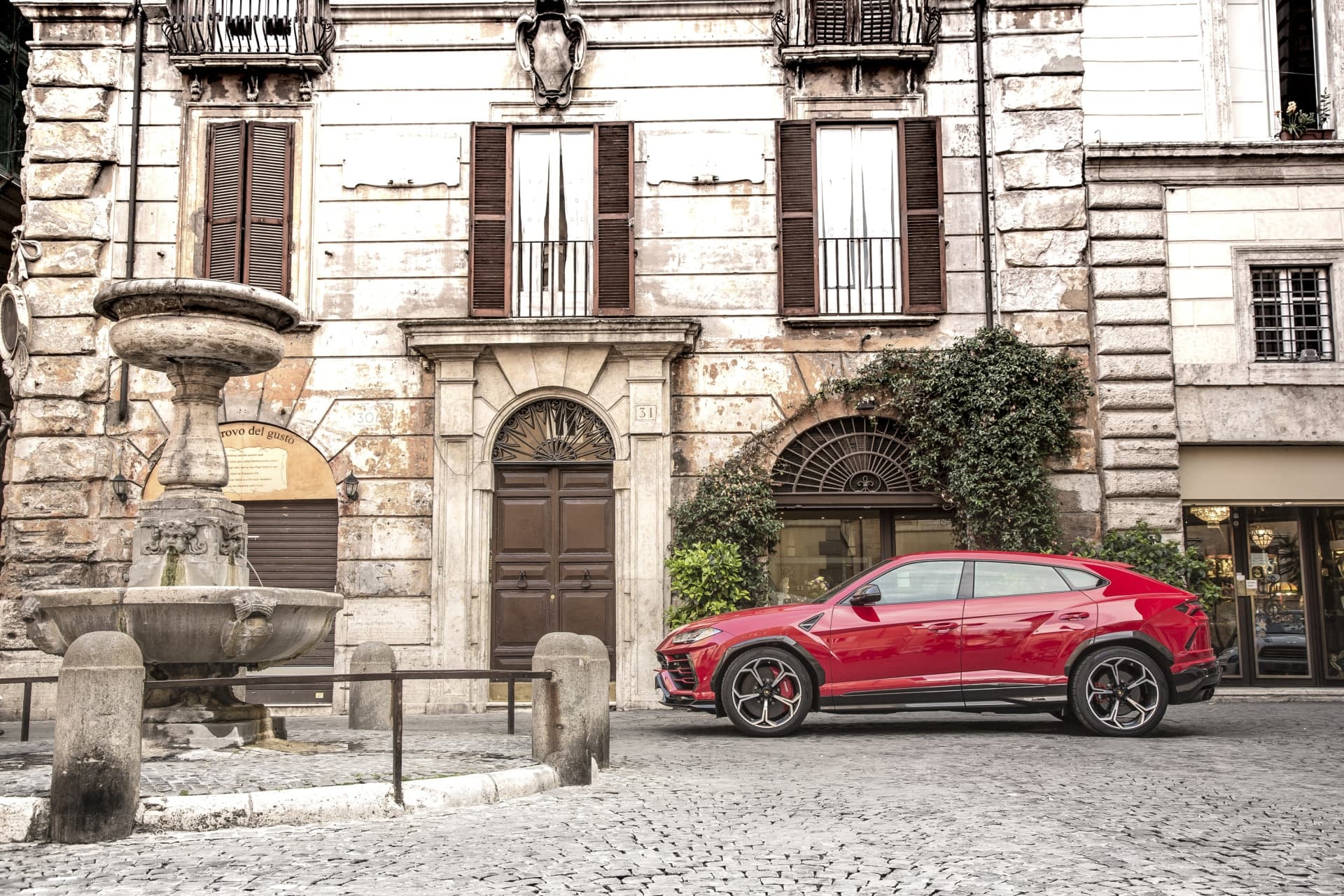 El Lamborghini Urus luce su línea lateral distintiva aparcado cerca de una fachada clásica.