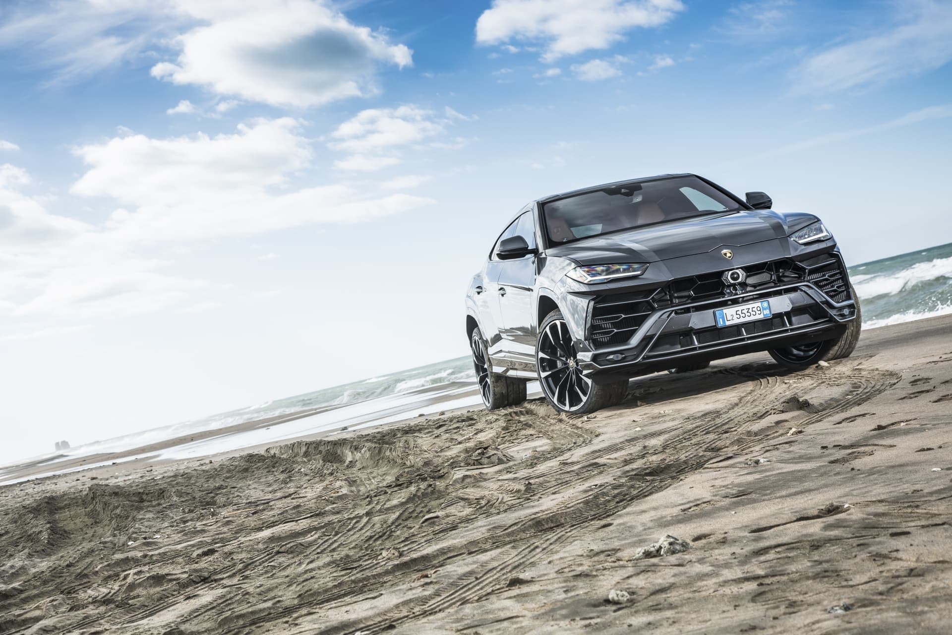 Perfil lateral y frontal del Lamborghini Urus en un entorno de dunas.