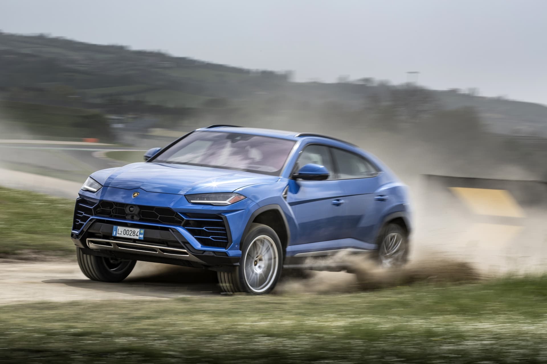 Perfil lateral del Urus azul destacando su estética y aerodinámica en un ambiente fuera de carretera.